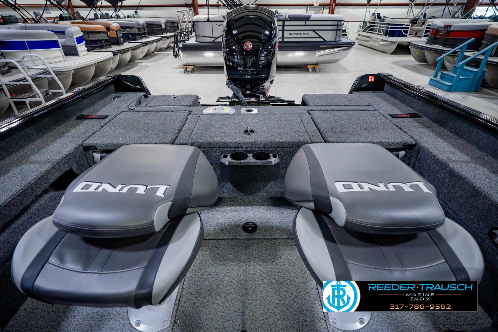 2026 Lund 1875 Impact XS boat interior with seating and motor, displayed in showroom.