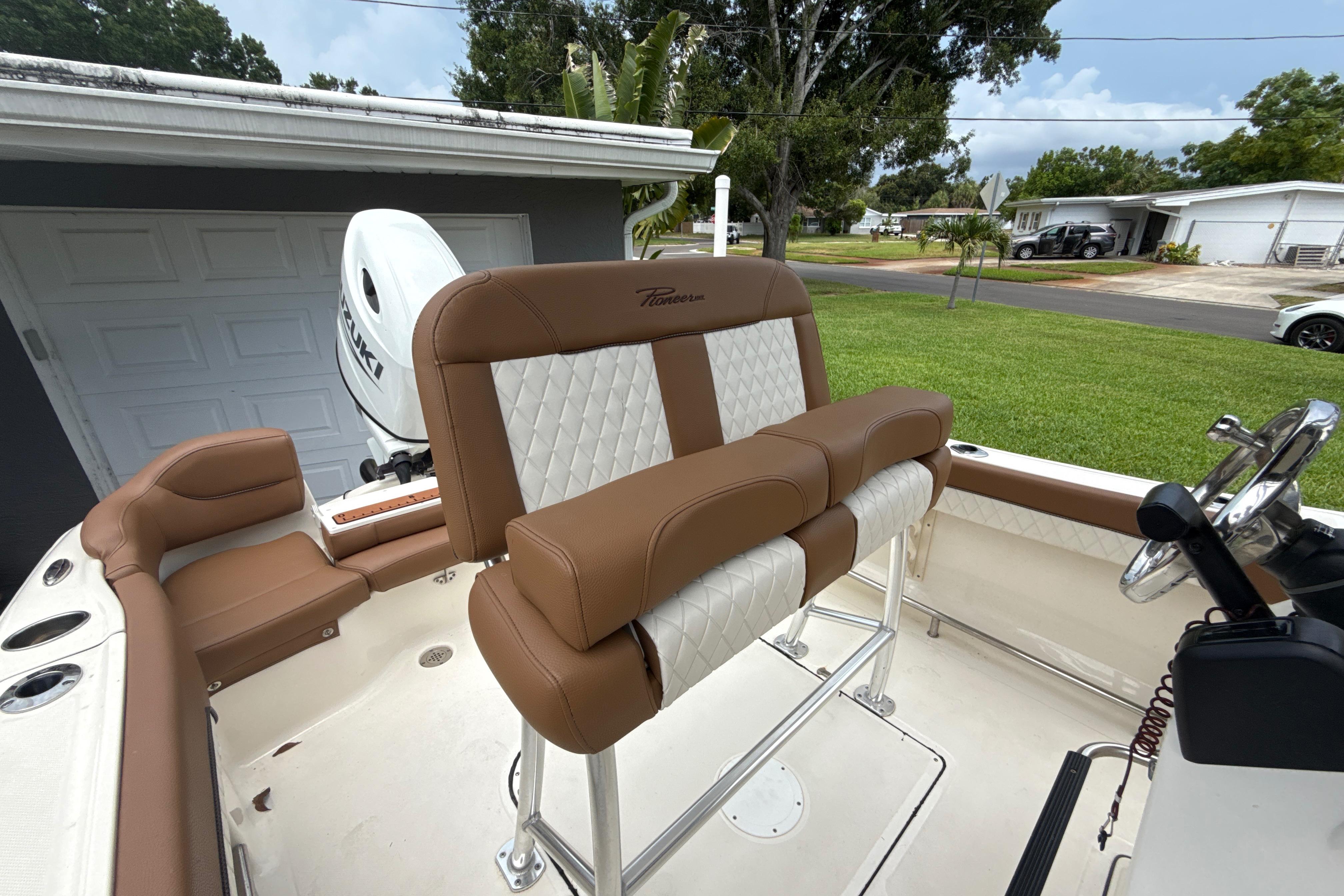 2023 Pioneer 202 Islander boat interior with brown and white seating, Suzuki engine visible.