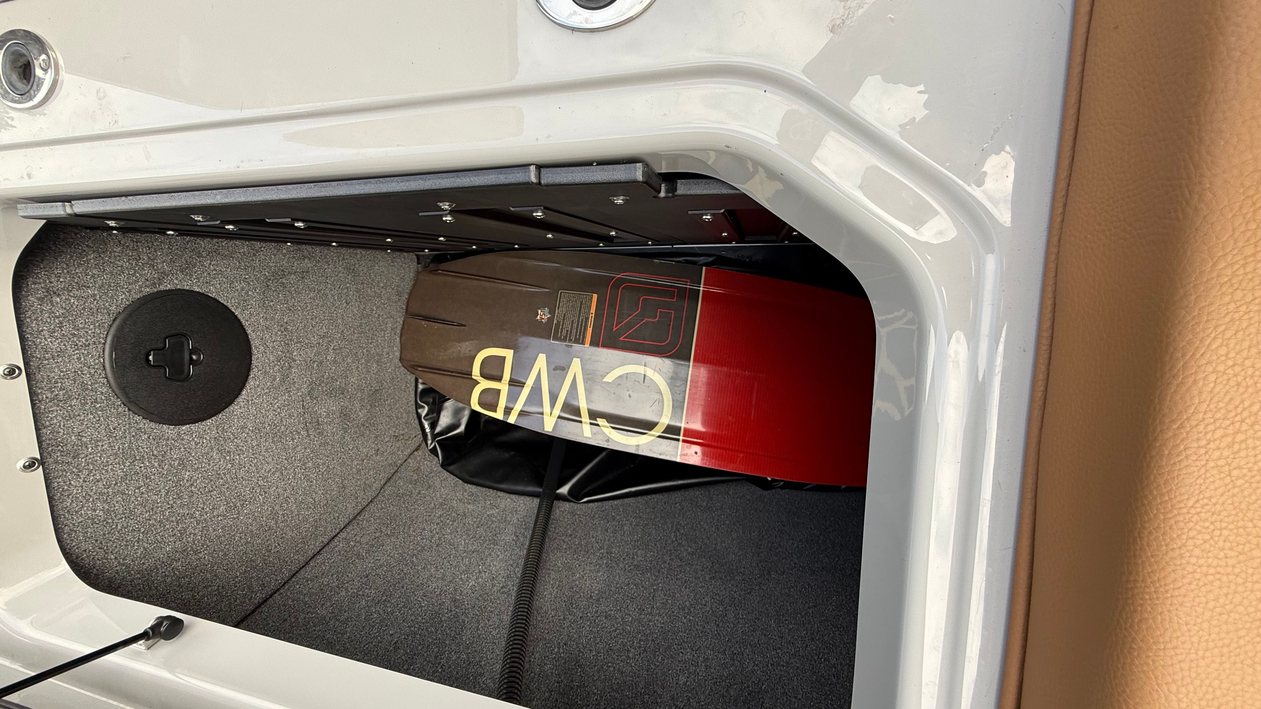 A storage compartment in a Malibu boat containing a wakeboard.