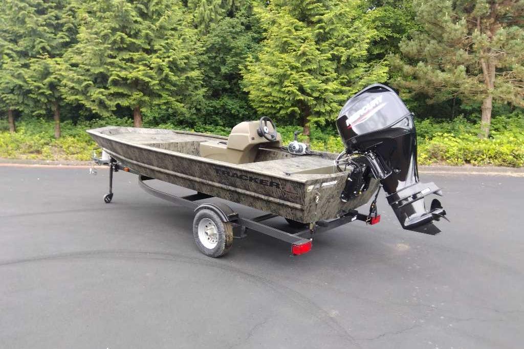 2026 Tracker Grizzly 1648 SC boat on trailer, parked outdoors near trees.