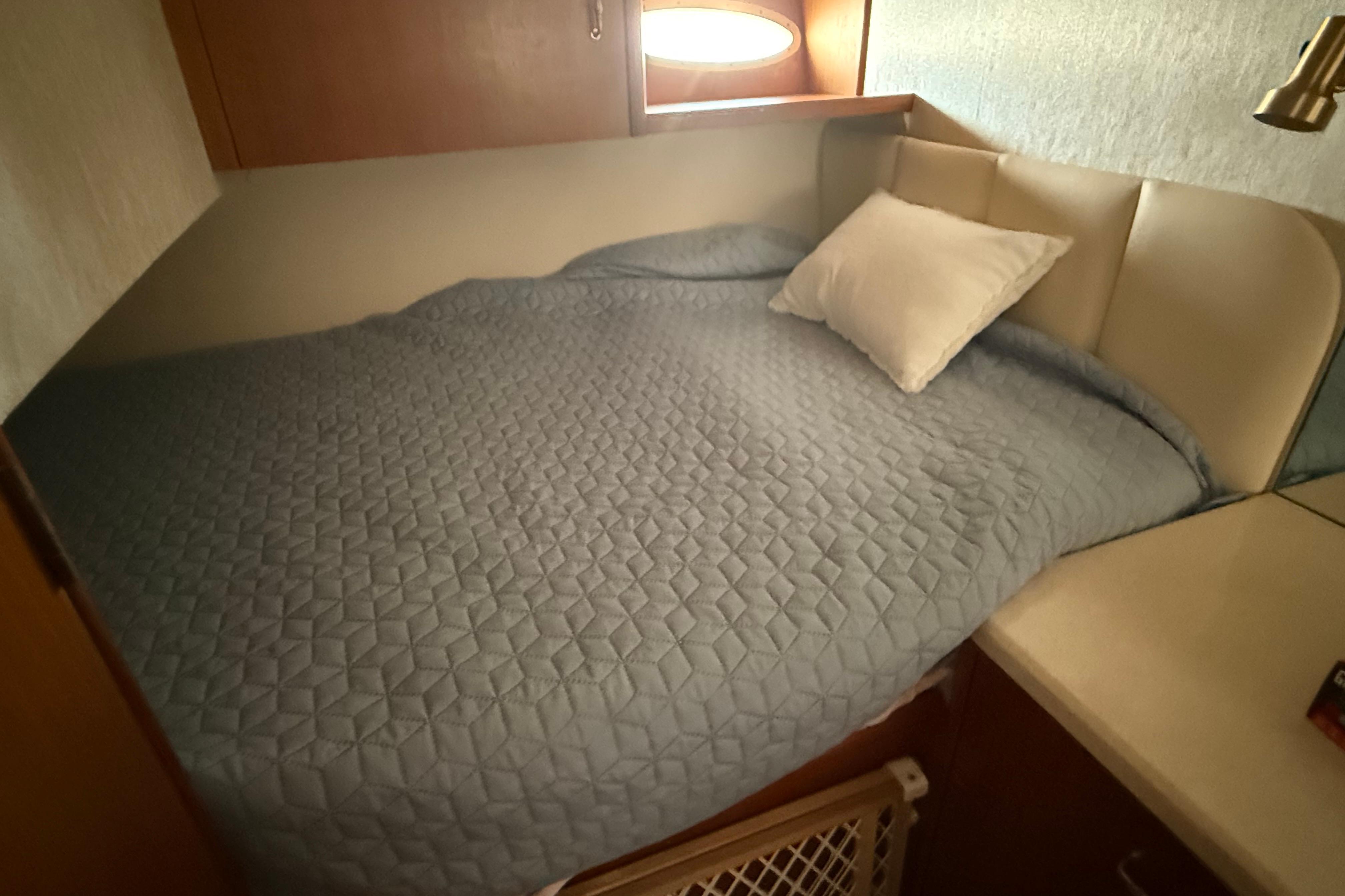 Cozy cabin bed in 1999 Ocean Yachts 40 Express, featuring a quilted blue cover.