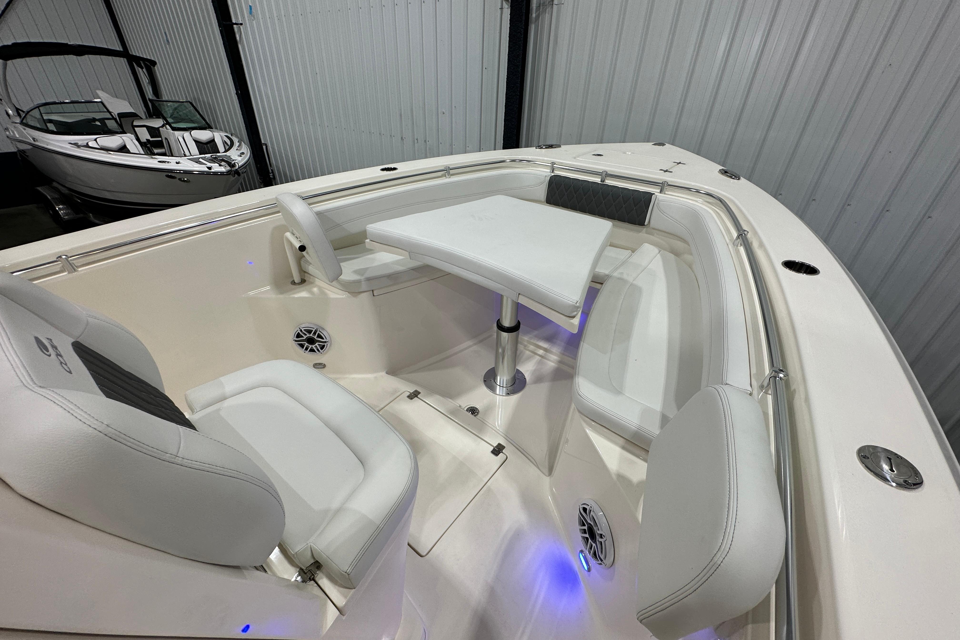2024 Cobia 301 Center Console boat interior with seating and table in a showroom.