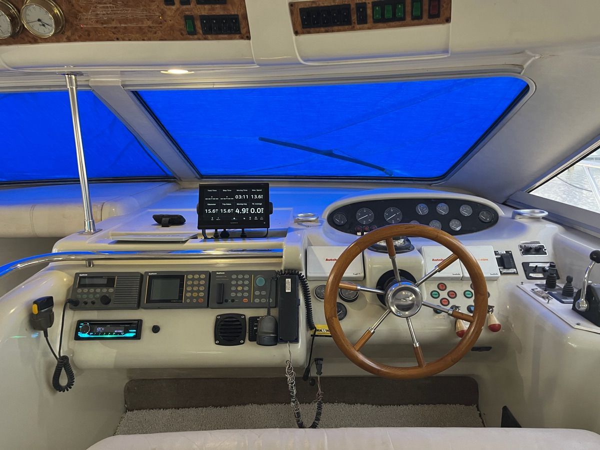 The image shows the cockpit of a 1999 Sealine F44 with a wooden steering wheel and modern instruments.