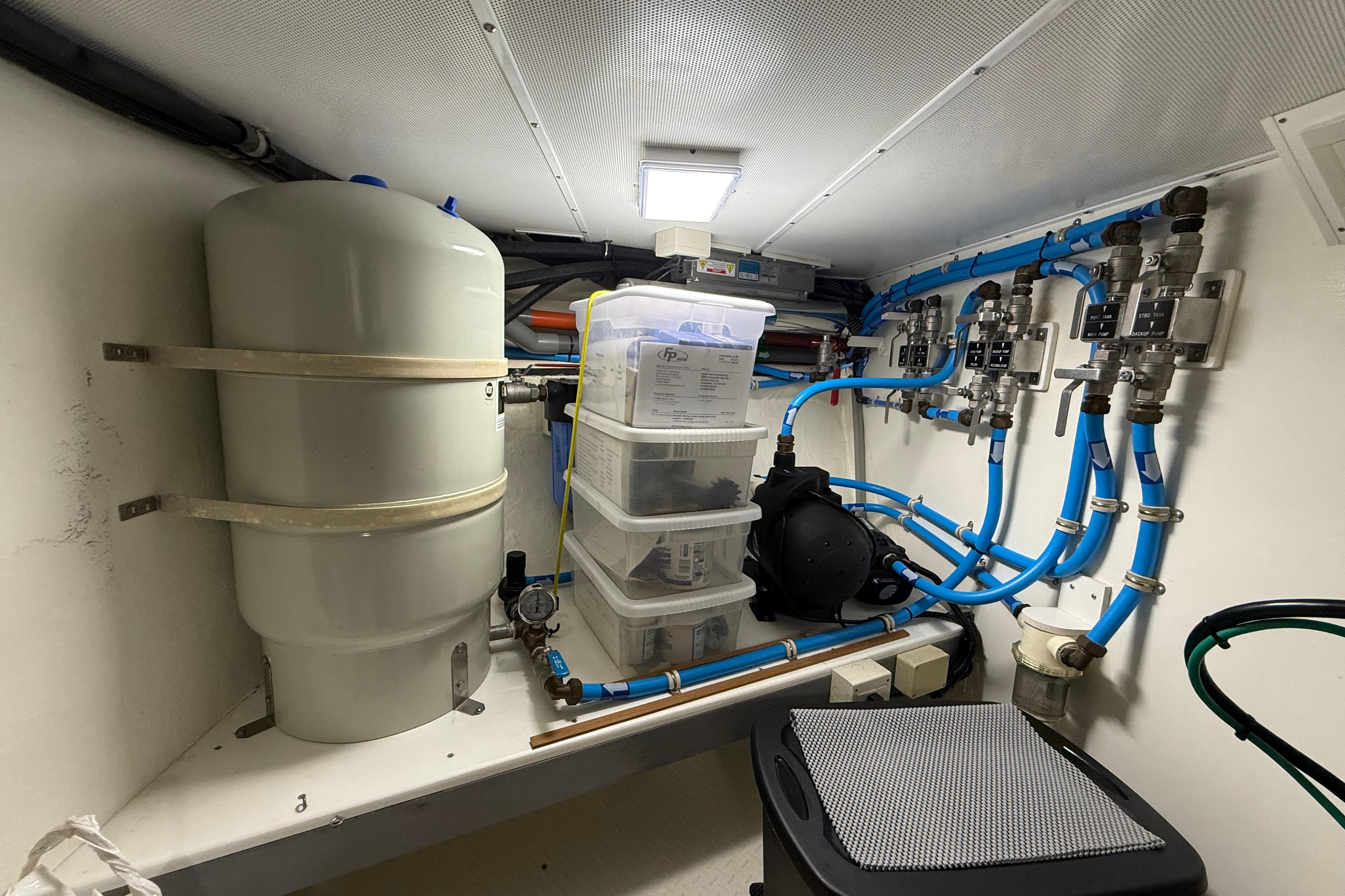 Engine room of 2009 Nordhavn N64 yacht with plumbing and storage containers.