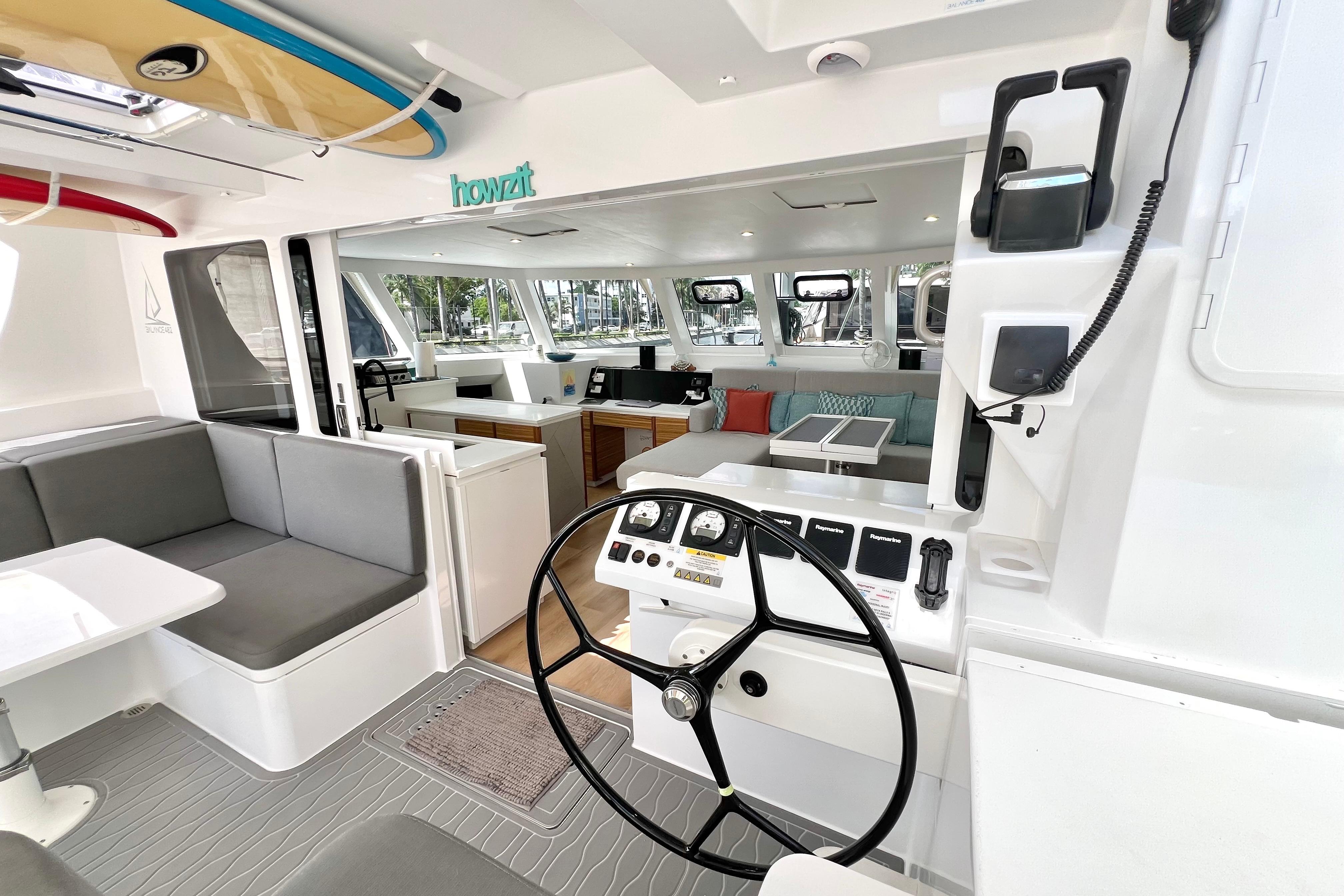 Interior of 2021 Balance 482 catamaran with modern helm, seating, and surfboards.