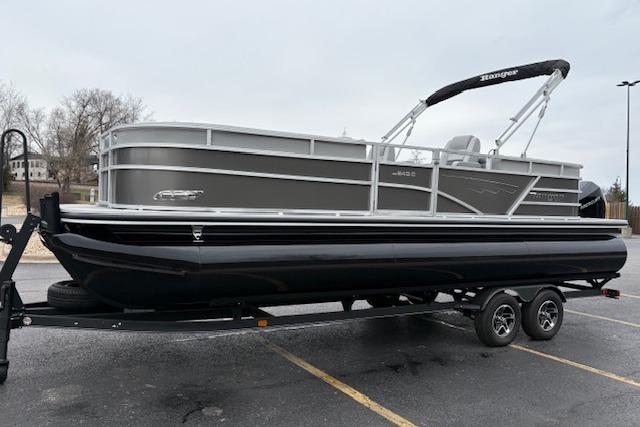 2025 Ranger Reata 243C pontoon boat on trailer in parking lot.