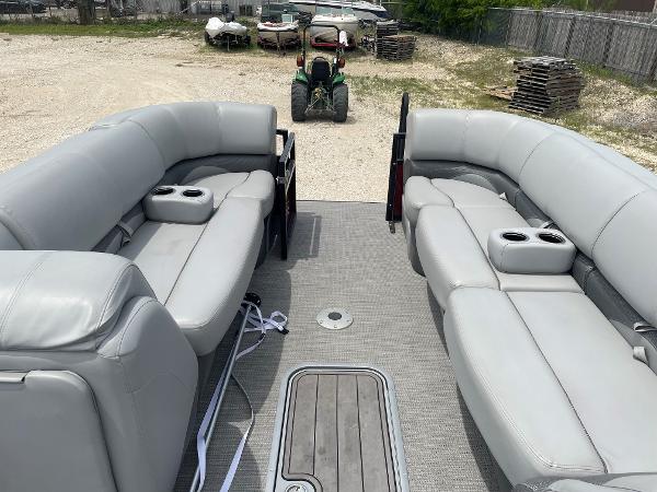 2023 Regency 250DL3 pontoon boat with spacious seating and cup holders, parked on gravel.