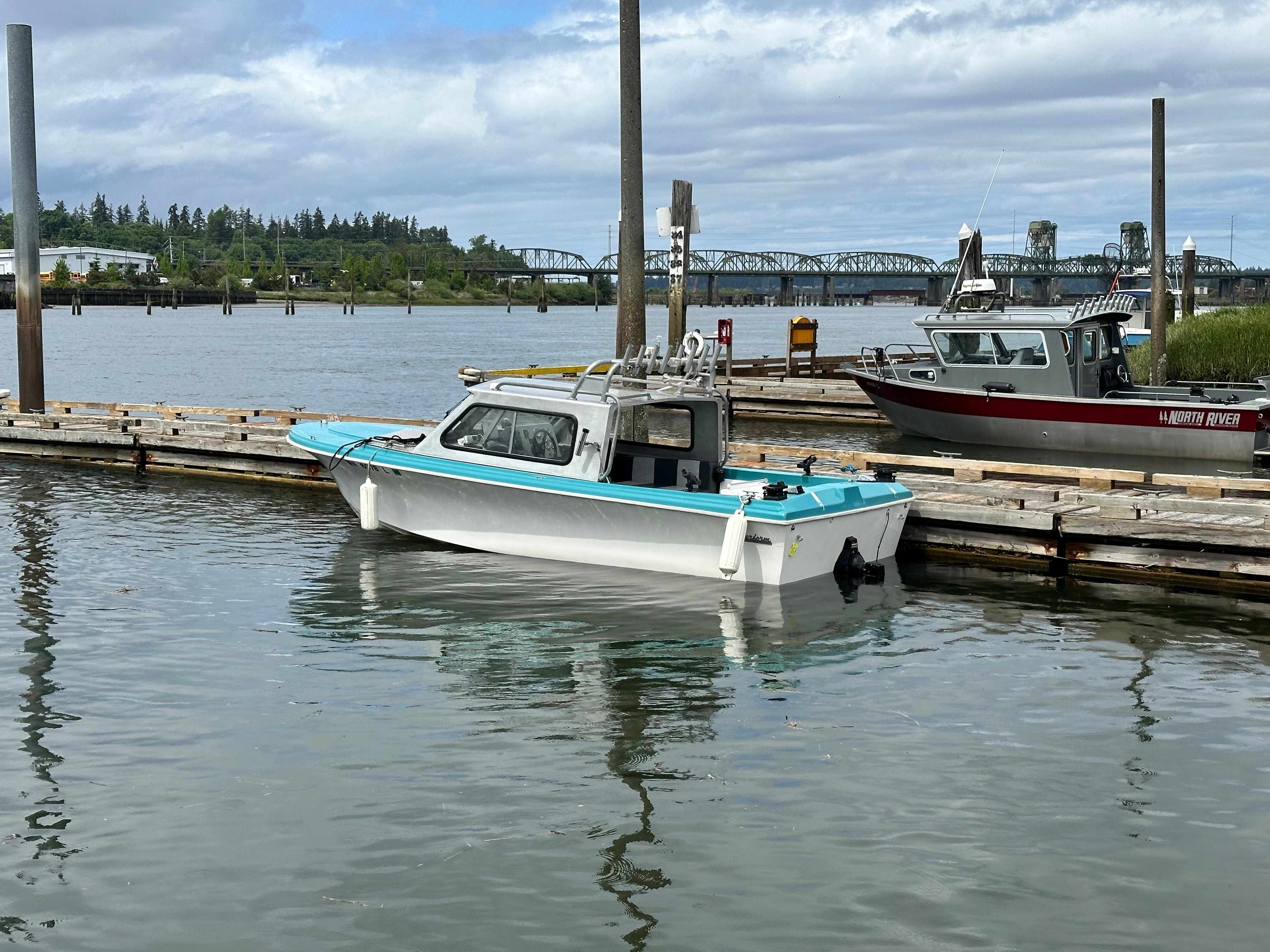 A restored 1967 Fiberform boat docked in calm waters under a cloudy sky.