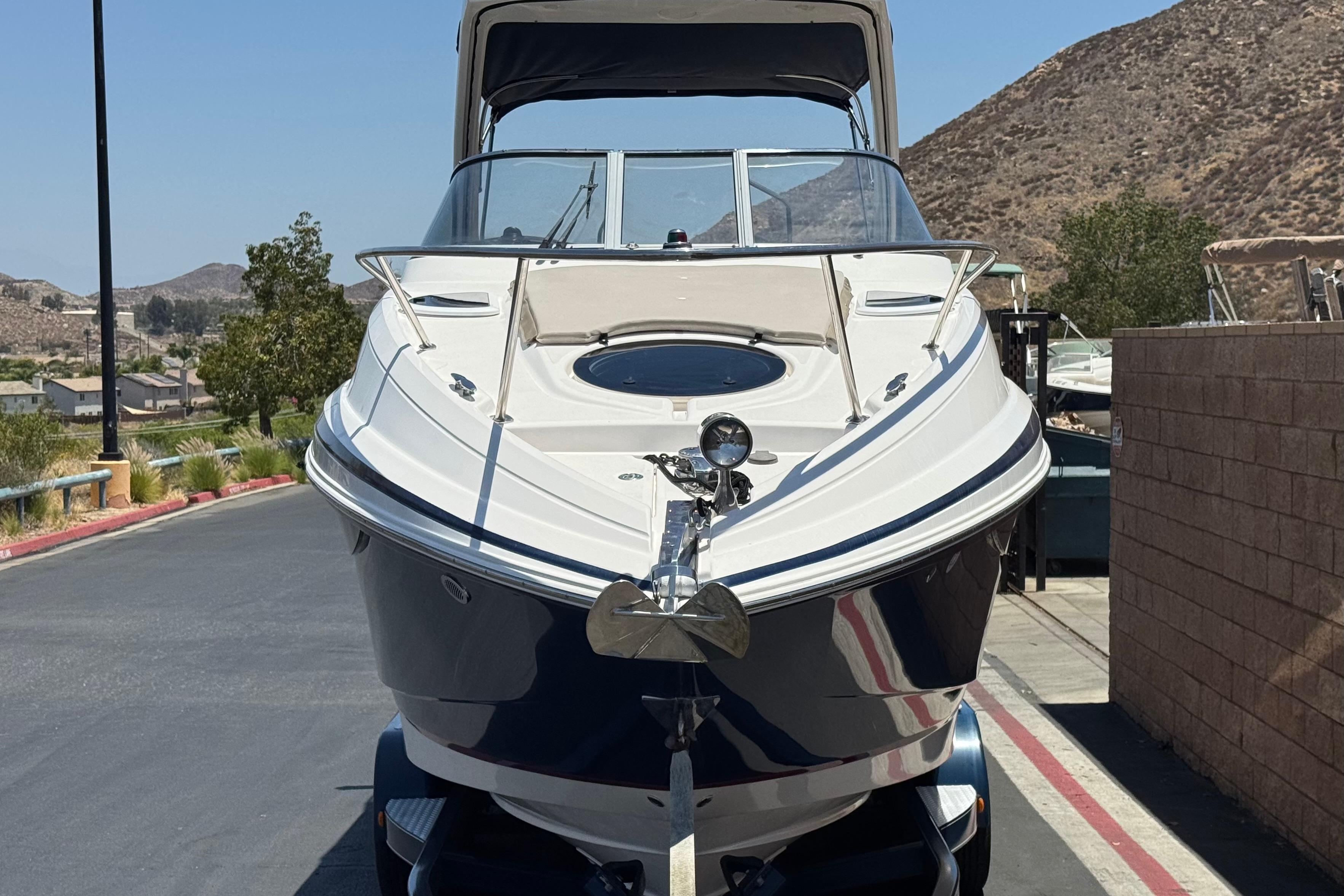 2013 Regal 28 Express boat on trailer, parked outdoors with scenic mountain backdrop.