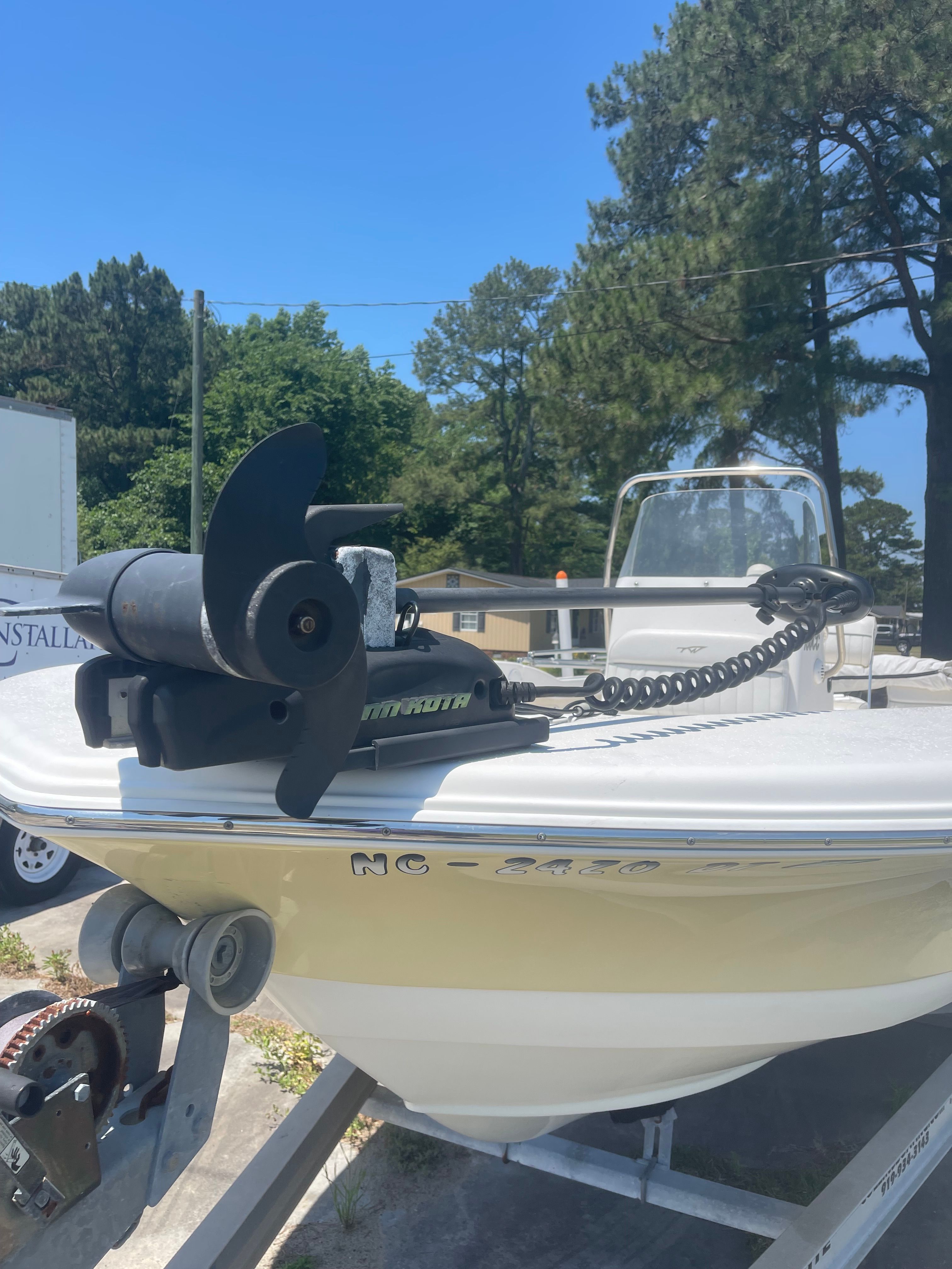 A Tidewater 180 CC Adventure boat on a trailer, surrounded by trees and buildings.