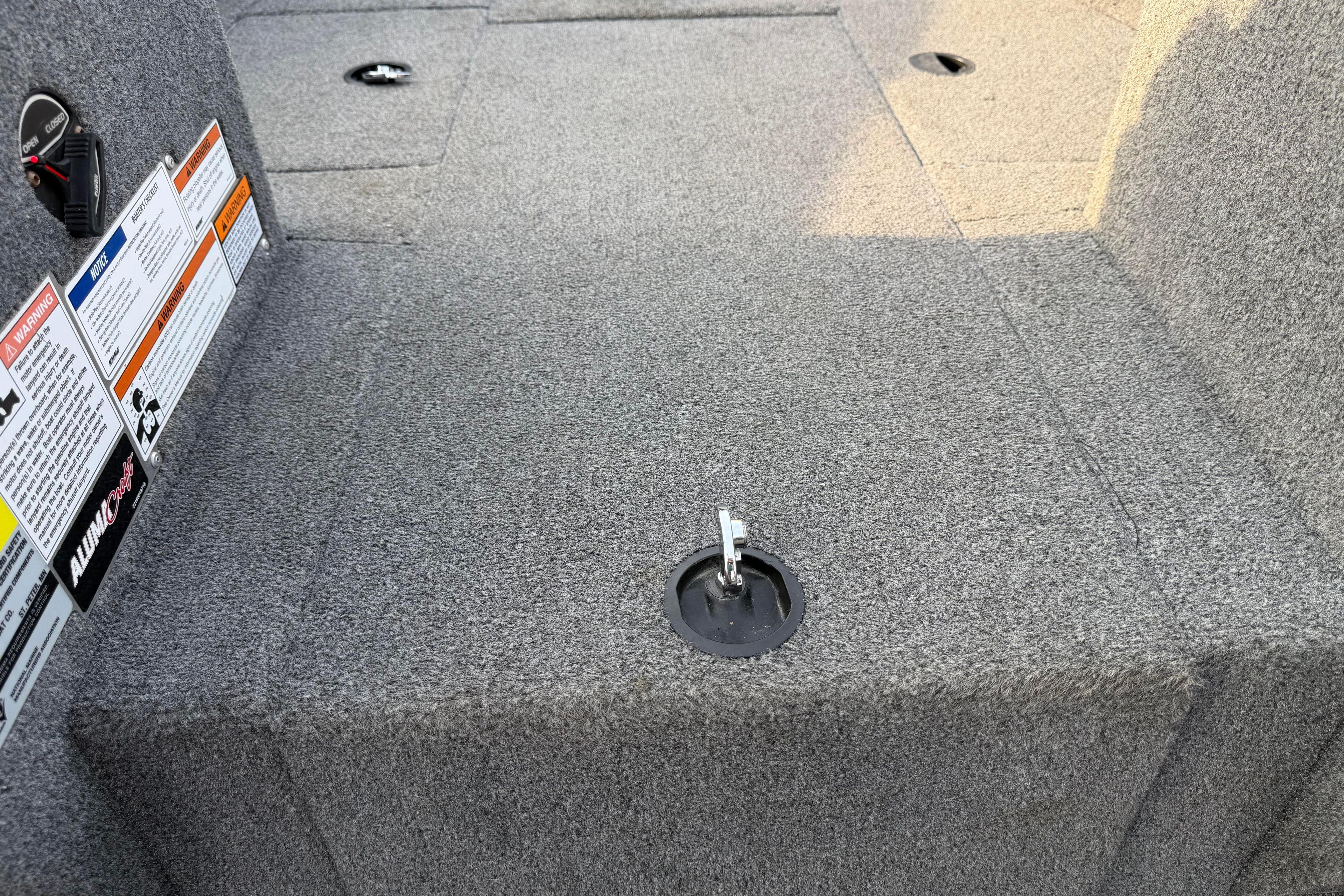 2019 Alumacraft Trophy 205 boat interior with carpeted flooring and safety labels.