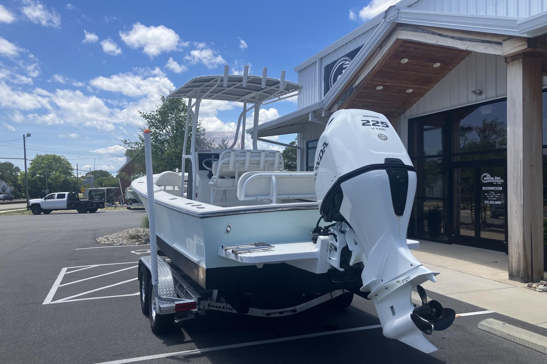 2022 May-Craft 2300 CCX boat with Honda 225 engine parked outside a showroom.