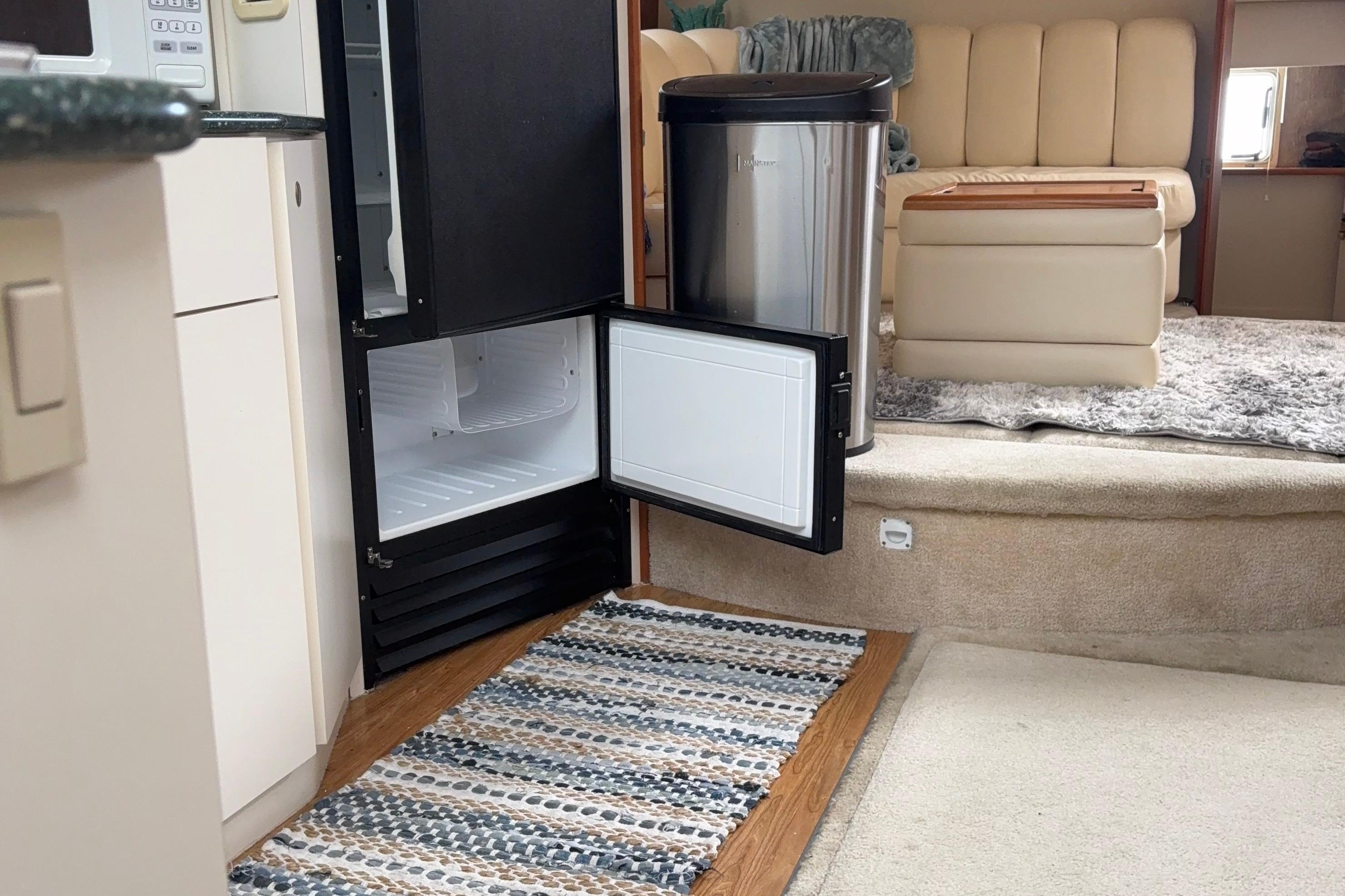 Interior of a 1999 Silverton 392 yacht with open fridge and cozy seating area.