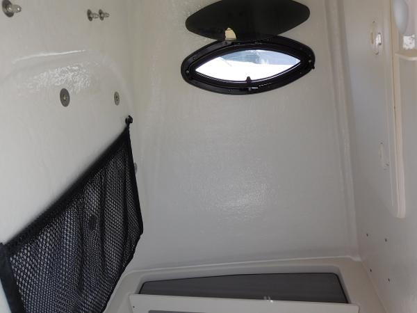 Interior cabin of 2024 Sailfish 242 CC boat with porthole and storage net.