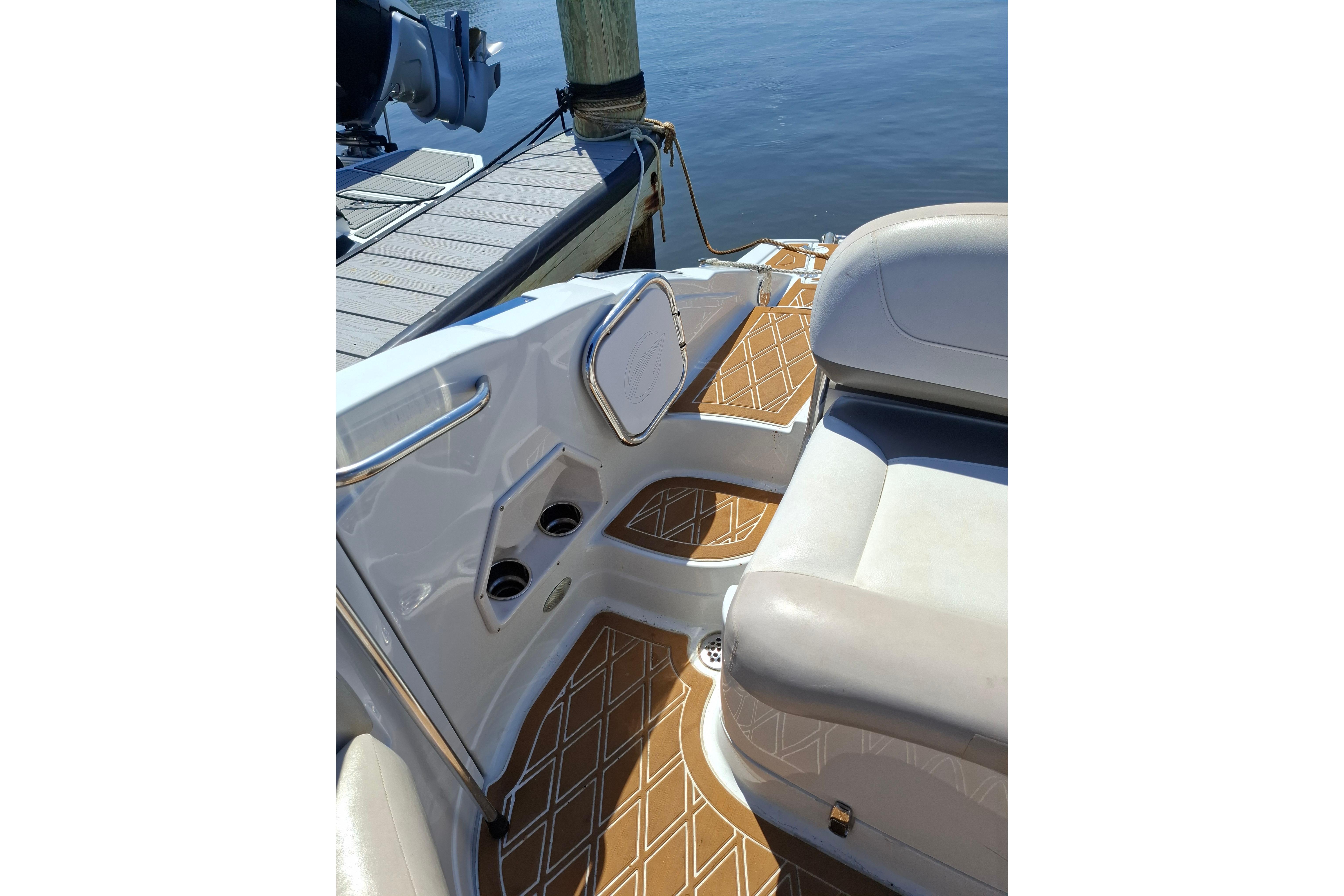 2013 Crownline Eclipse E6 boat interior with cushioned seating and stylish flooring near a dock.