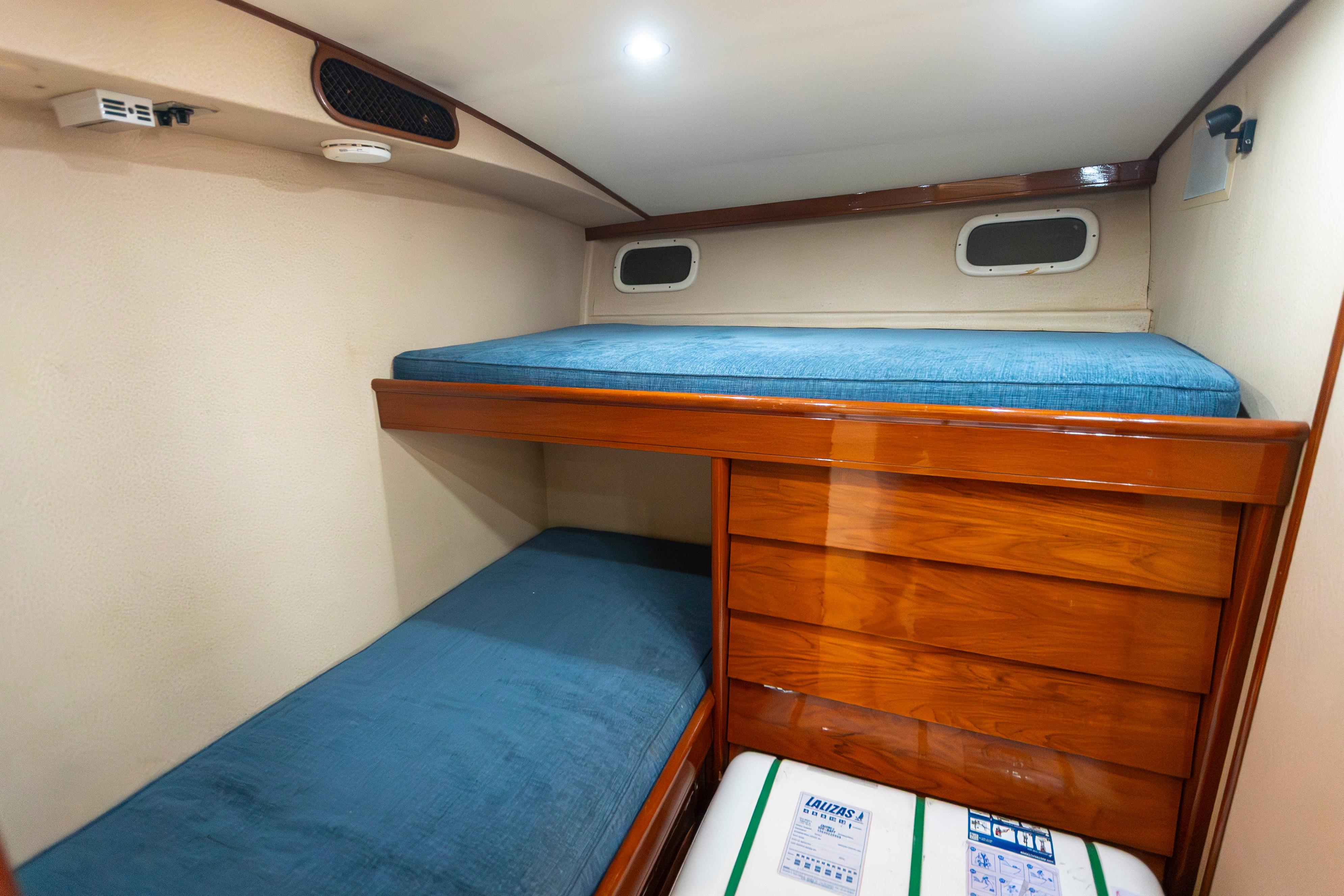 1972 Rybovich Convertible cabin with wooden bunk beds and blue cushions.