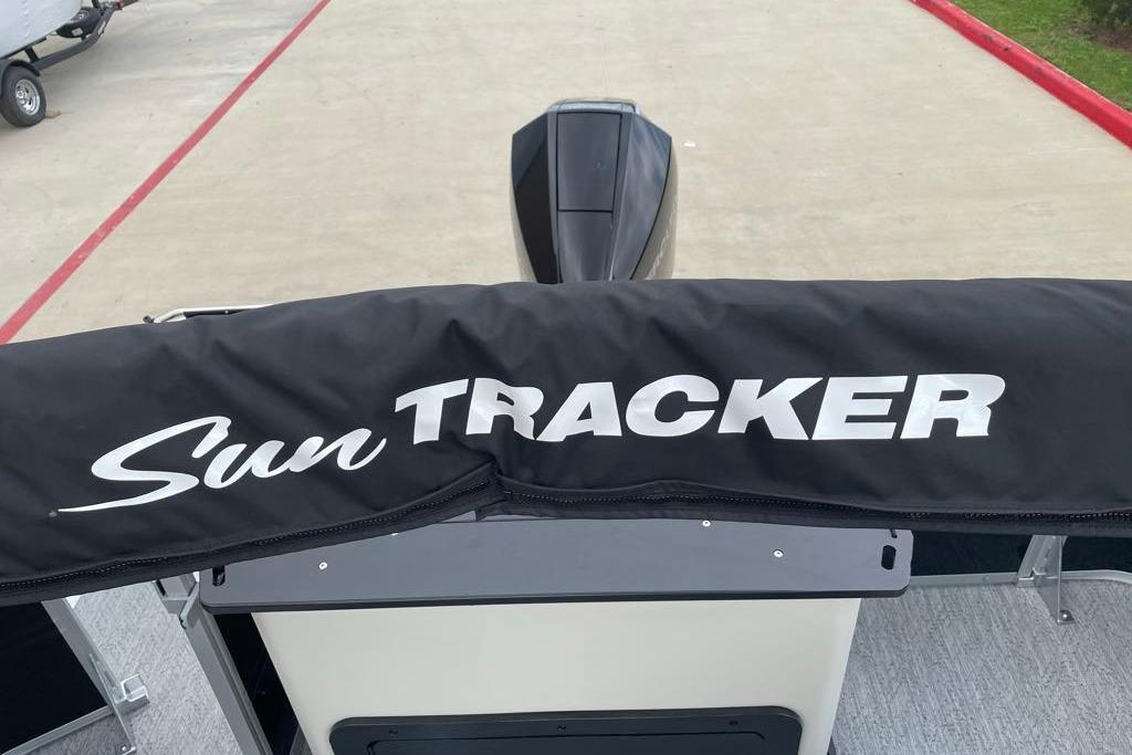 2026 Sun Tracker Fishin' Barge 22 XP3 boat cover with logo, parked on concrete.