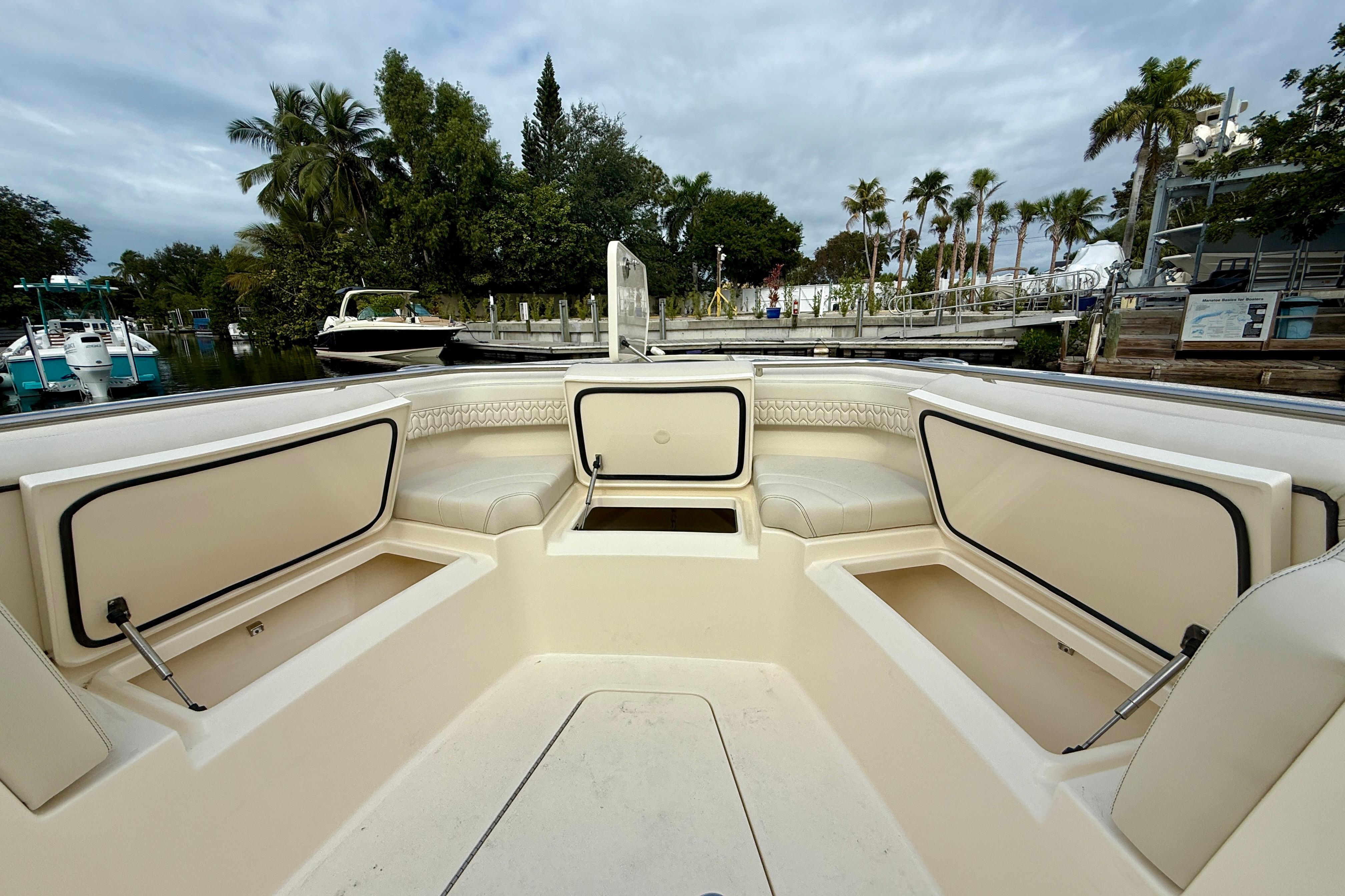2026 Scout 288 LXF boat interior with seating and storage, docked near palm trees.
