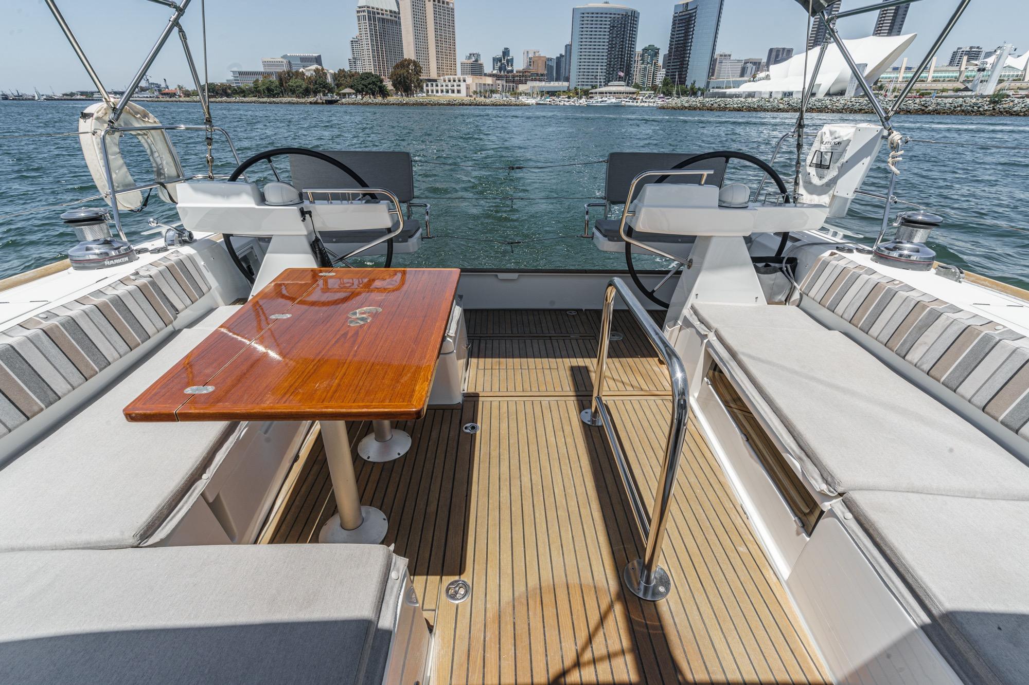 Cockpit of 2017 Beneteau Sense 50 yacht with dual steering wheels and wooden table.