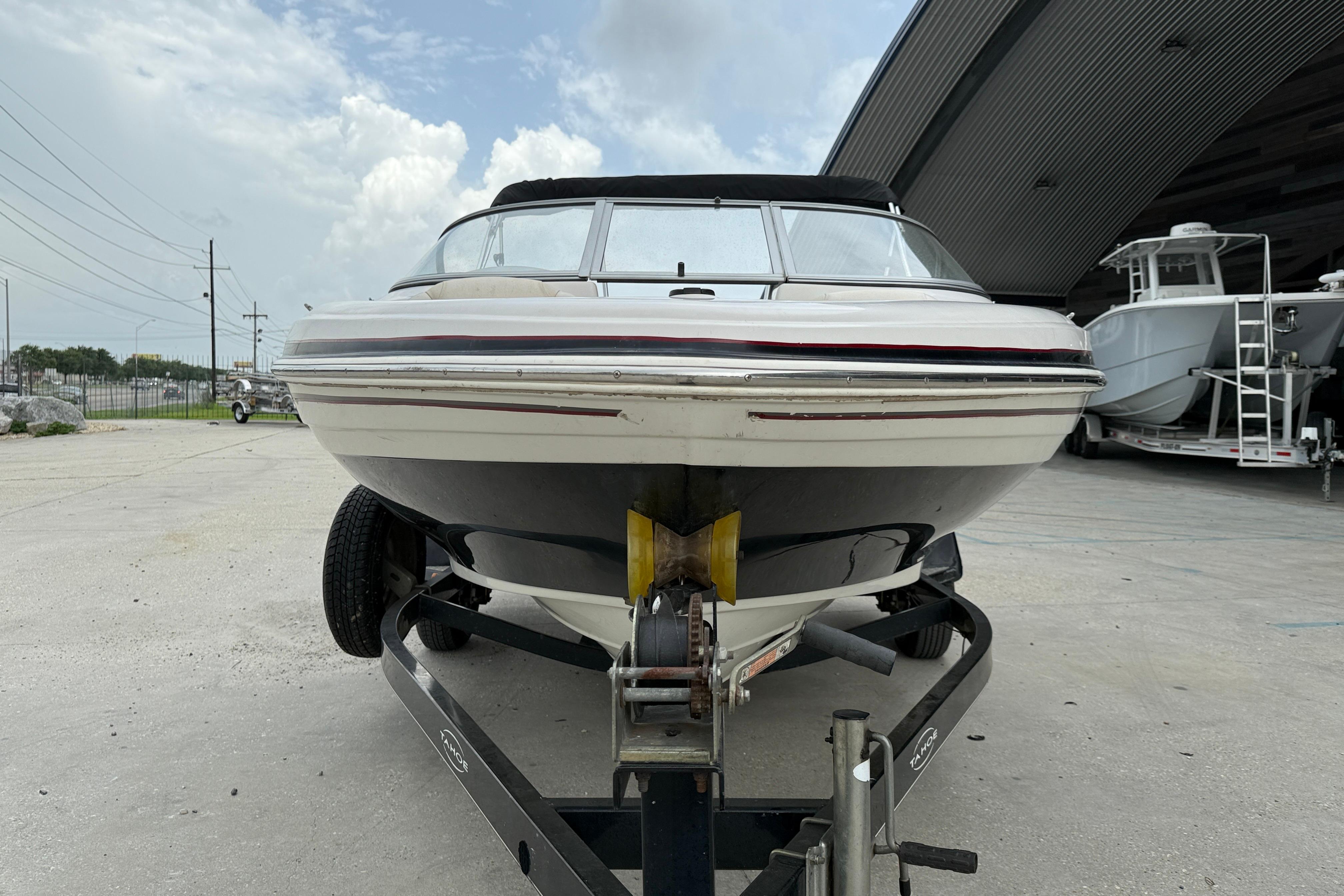 2010 Tahoe Q4 boat on trailer, parked outdoors under cloudy sky.