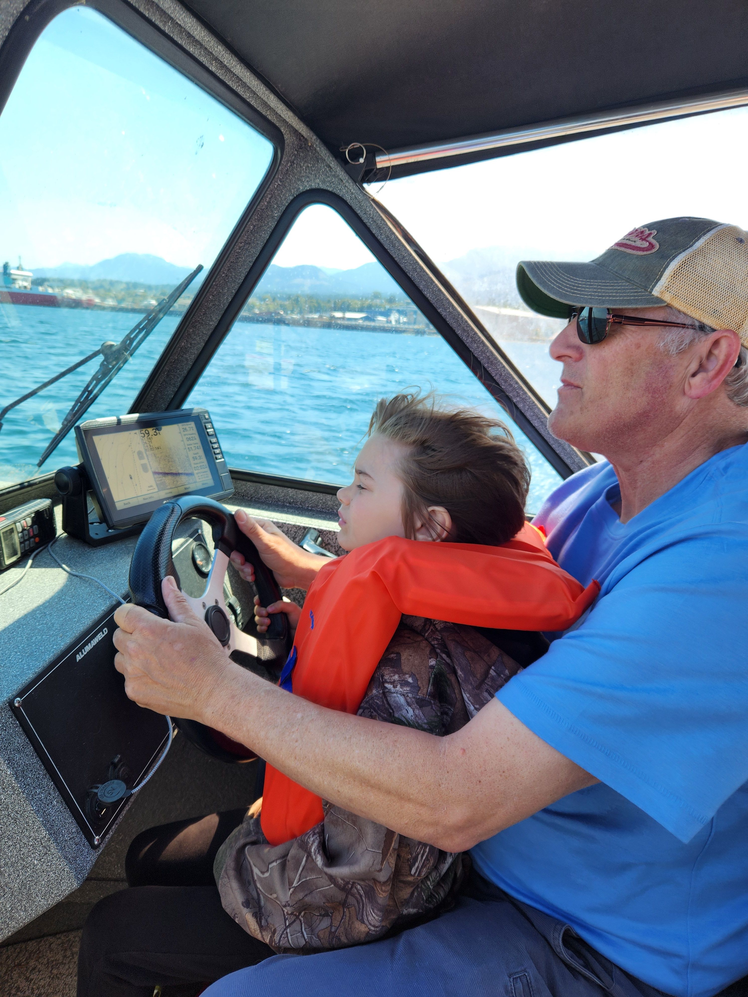 Man and child steering 2020 Alumaweld Talon 18 boat on the water.