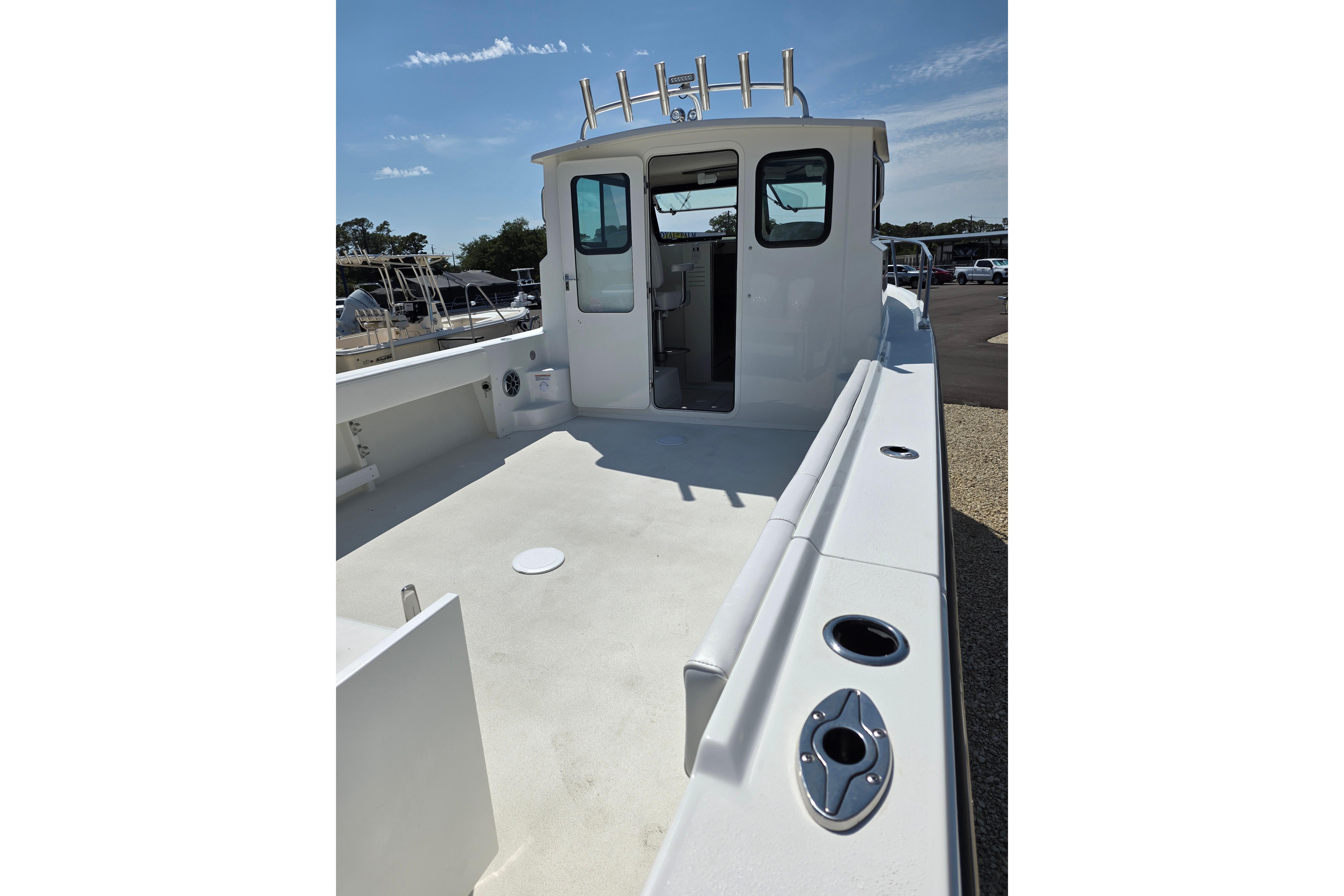 2026 Parker 287 Explorer boat deck with cabin, rod holders, and clear sky.