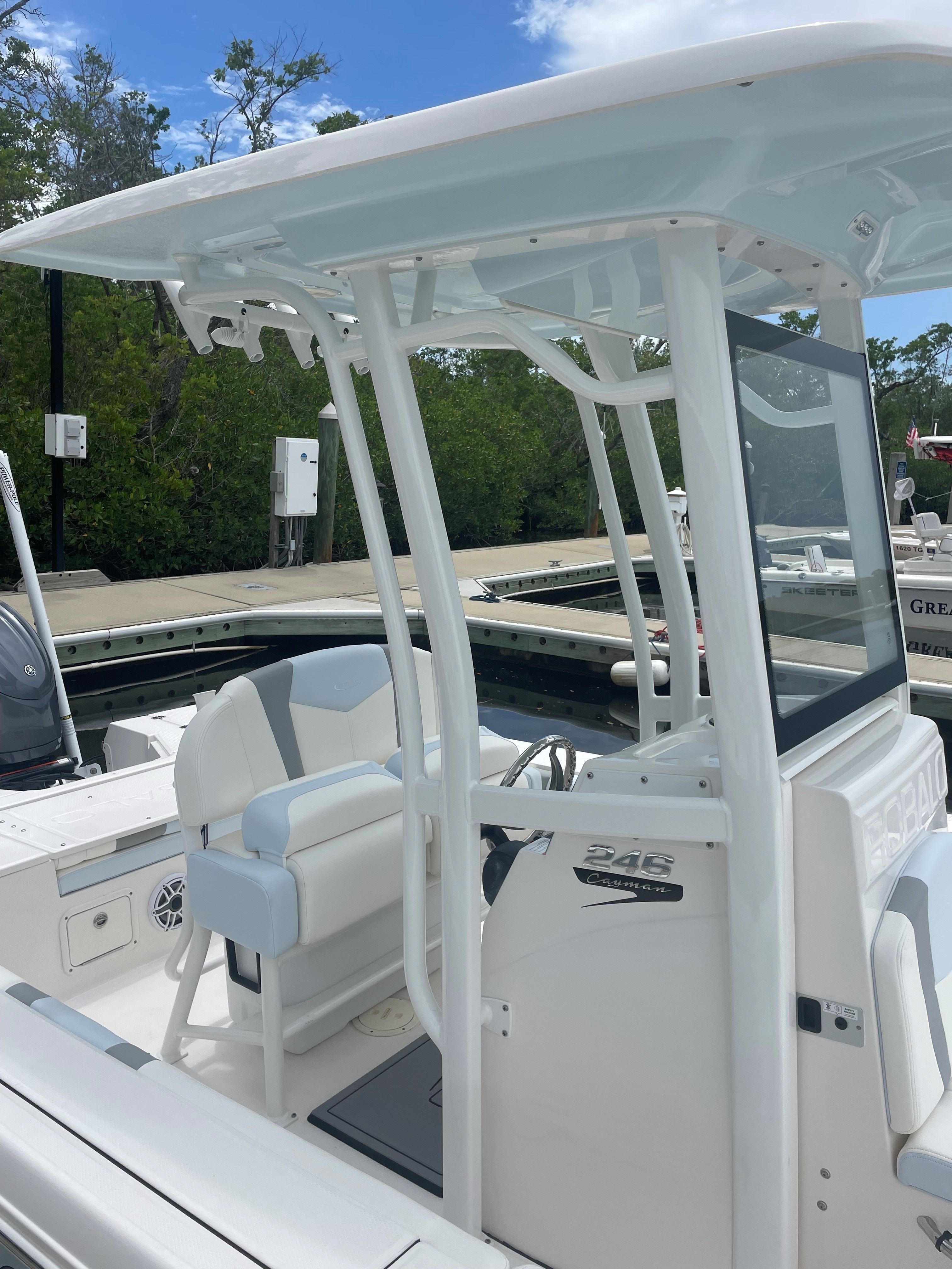The image shows a modern boat with a white T-top and cushioned seating.