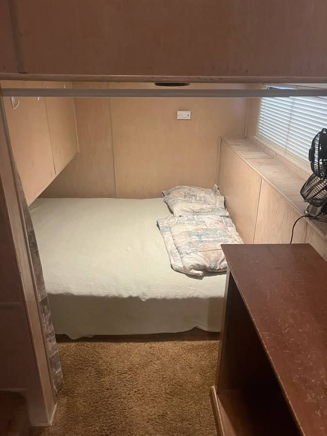 Interior of a 1993 Lakeview houseboat with bed and fan.