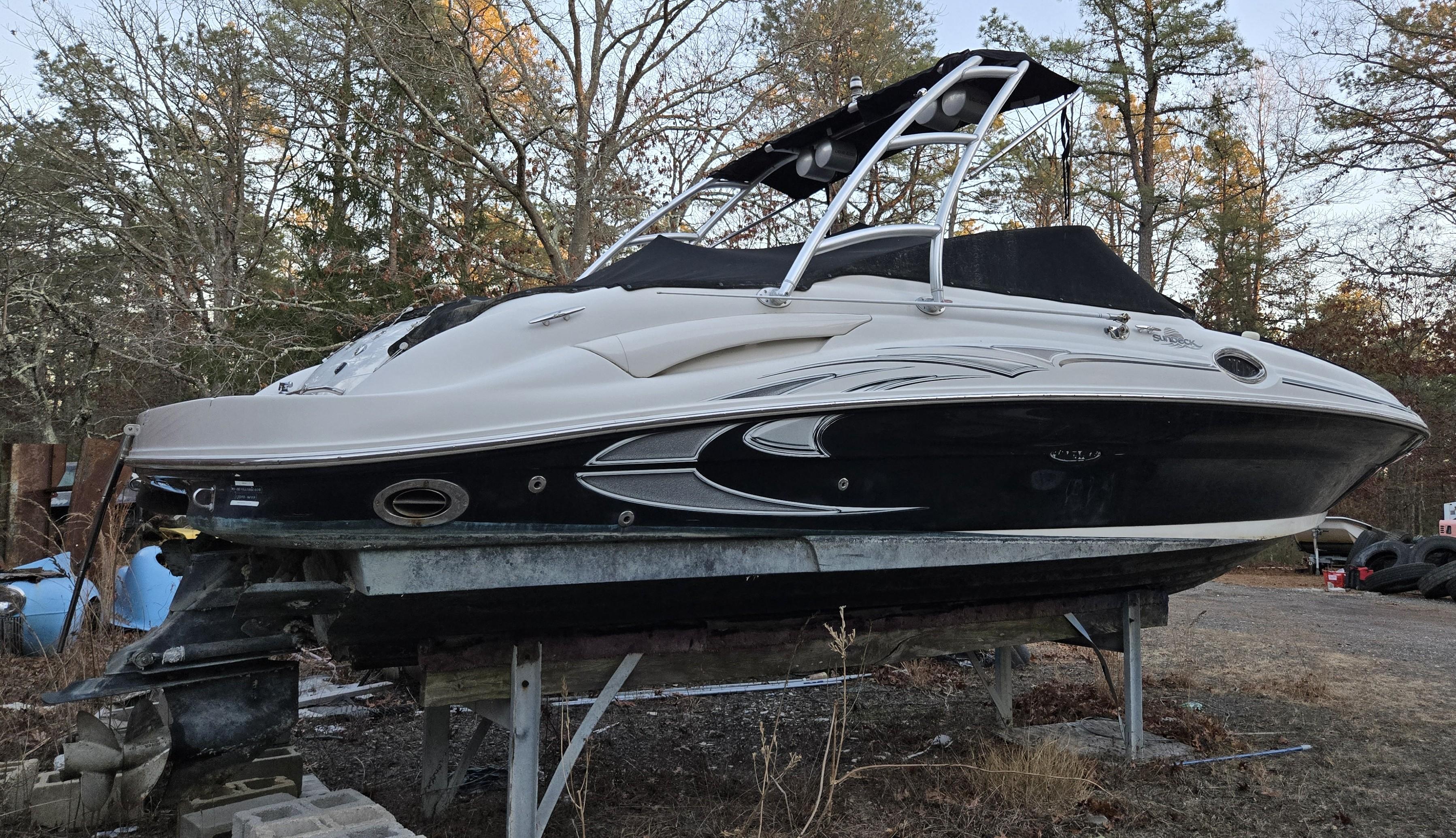 2006 Sea Ray 270 Sundeck boat on dry land, surrounded by trees.