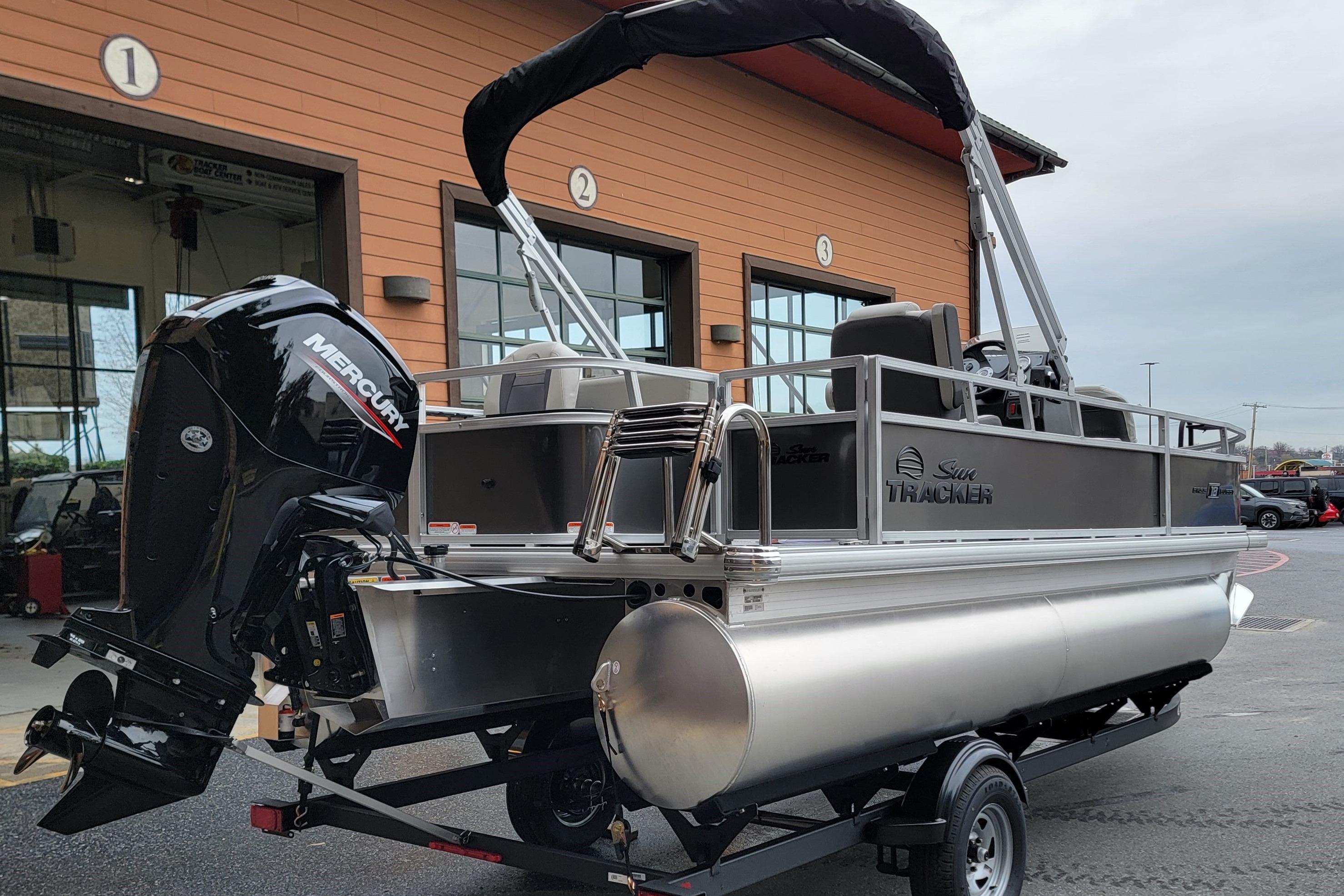 2026 Sun Tracker Bass Buggy 18 DLX pontoon boat with Mercury engine, parked outside.
