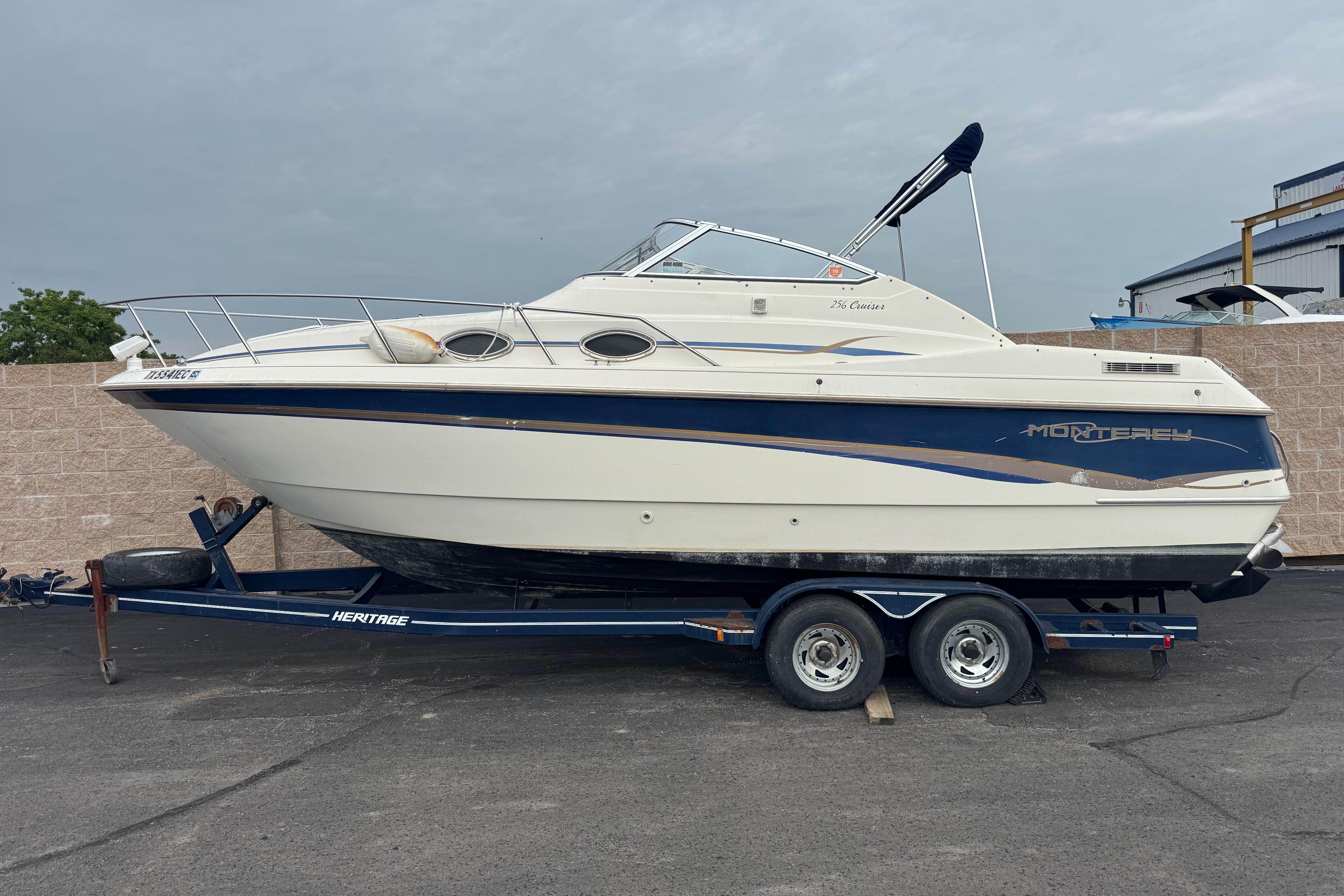 1997 Monterey 256 Cruiser boat on trailer, parked outdoors.