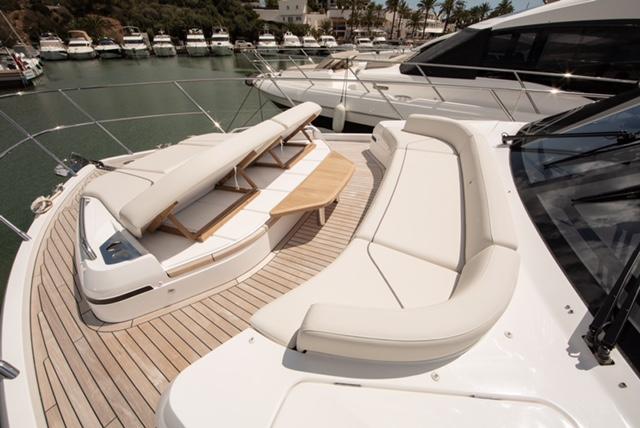2024 Princess V55 yacht with luxurious deck seating and sunbeds in a marina.