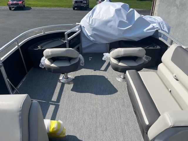 2026 Sun Tracker Fishin' Barge 20 DLX interior with seating and covered equipment.