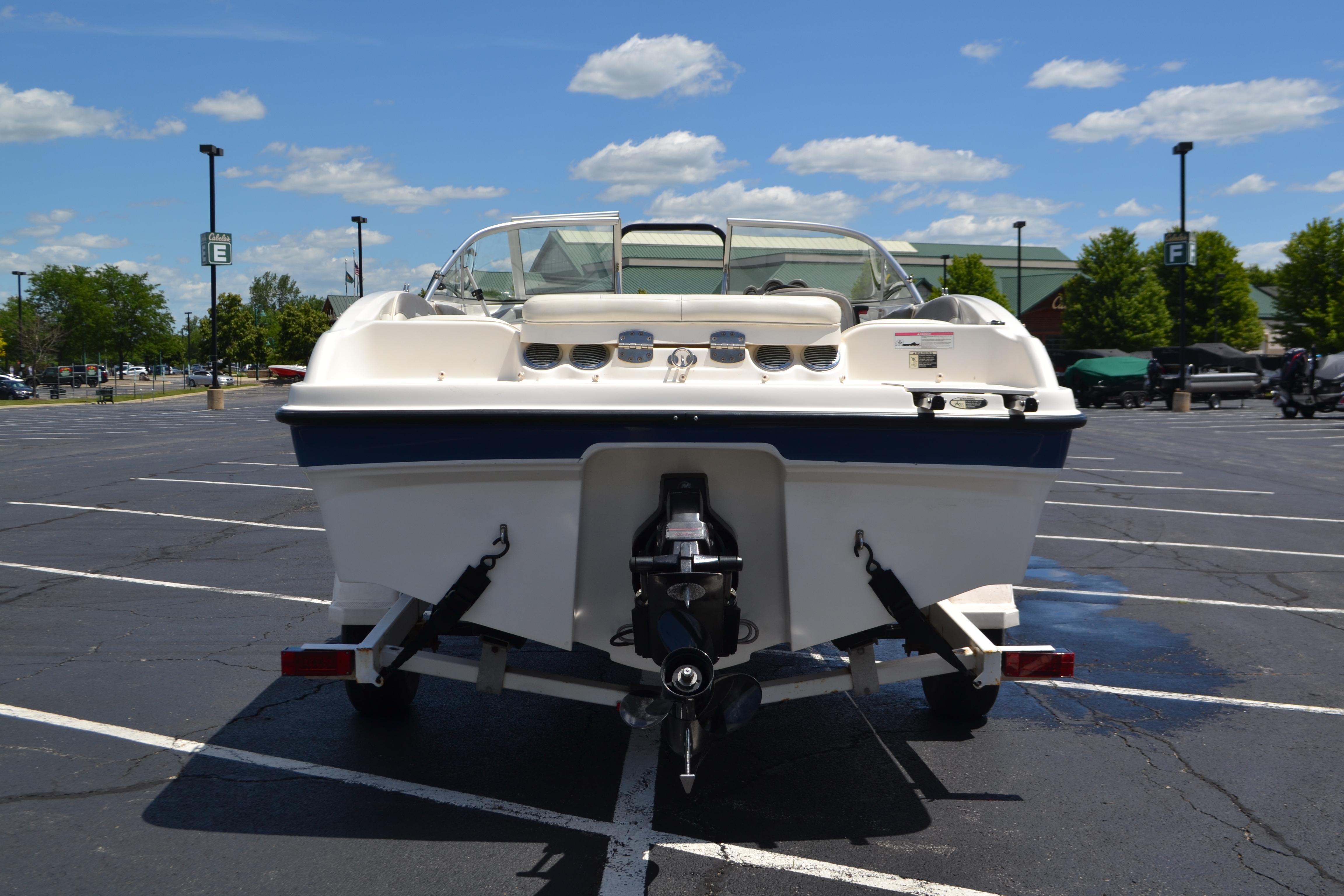 2009 Bayliner 185 Bowrider on trailer in parking lot under blue sky.