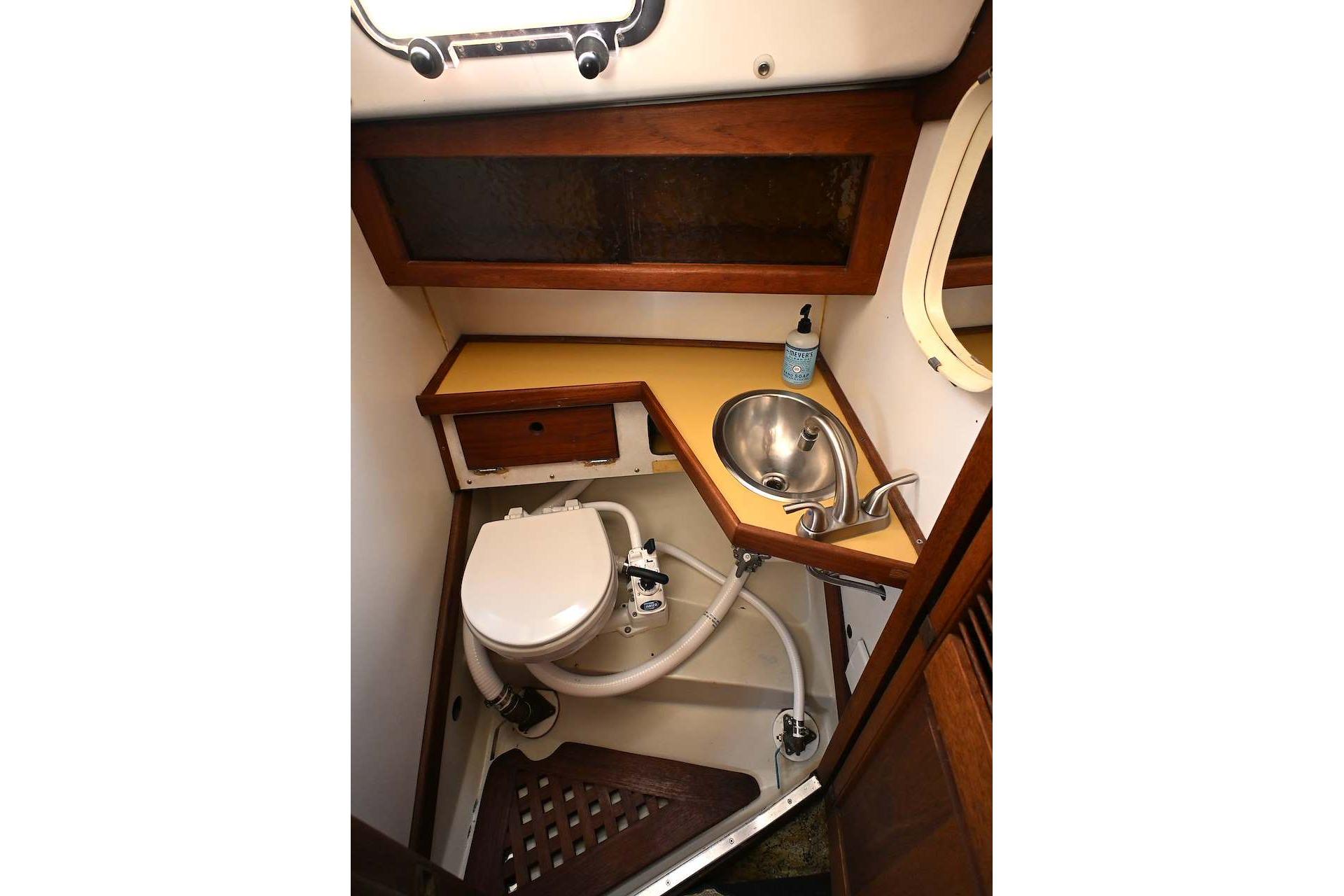 1977 Mercator Offshore boat bathroom with sink, toilet, and wooden cabinetry.