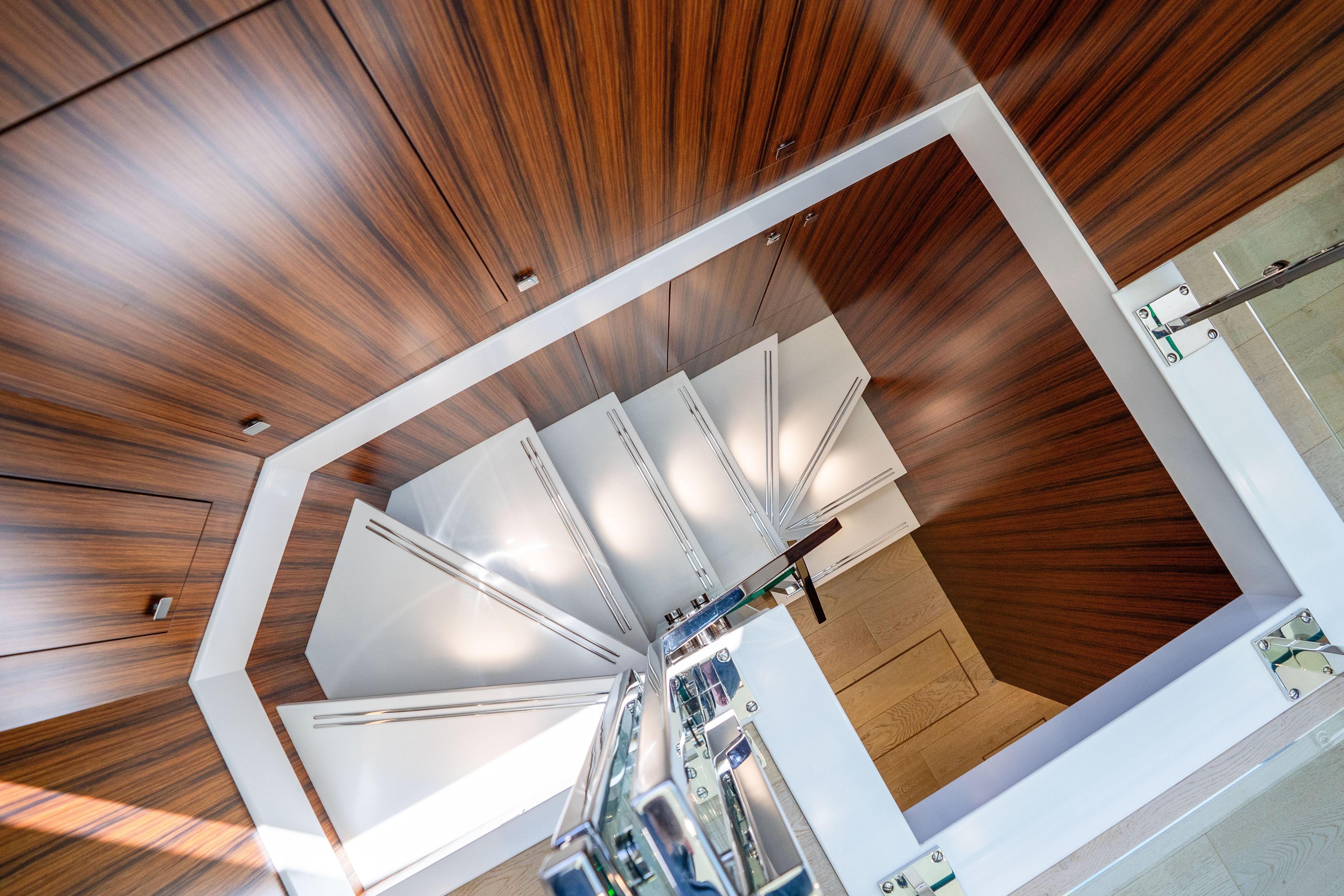 Elegant spiral staircase with wood paneling on a 2021 Hatteras M75 Panacera yacht.