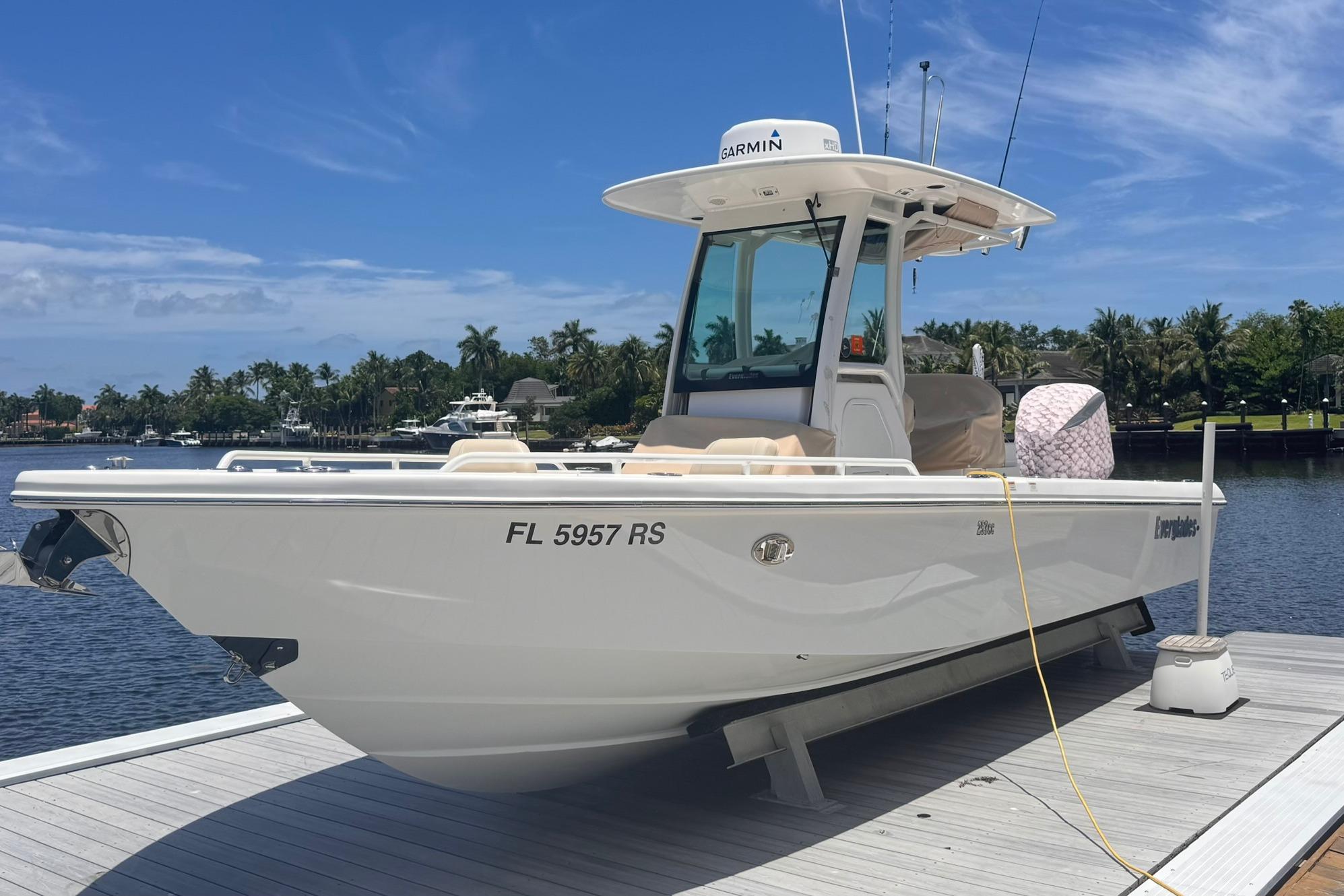 2018 Everglades 253 Center Console boat docked by a scenic waterfront.
