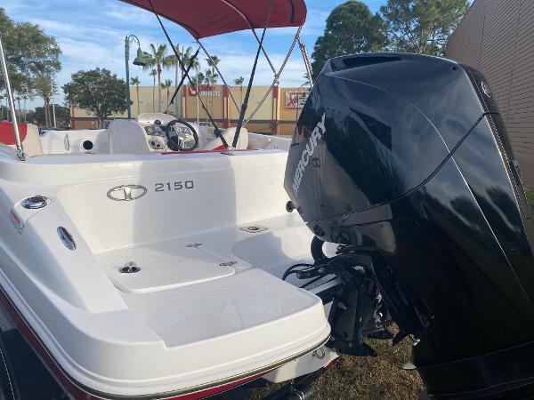 2022 Tahoe 2150 boat with outboard motor and red canopy, parked outdoors.