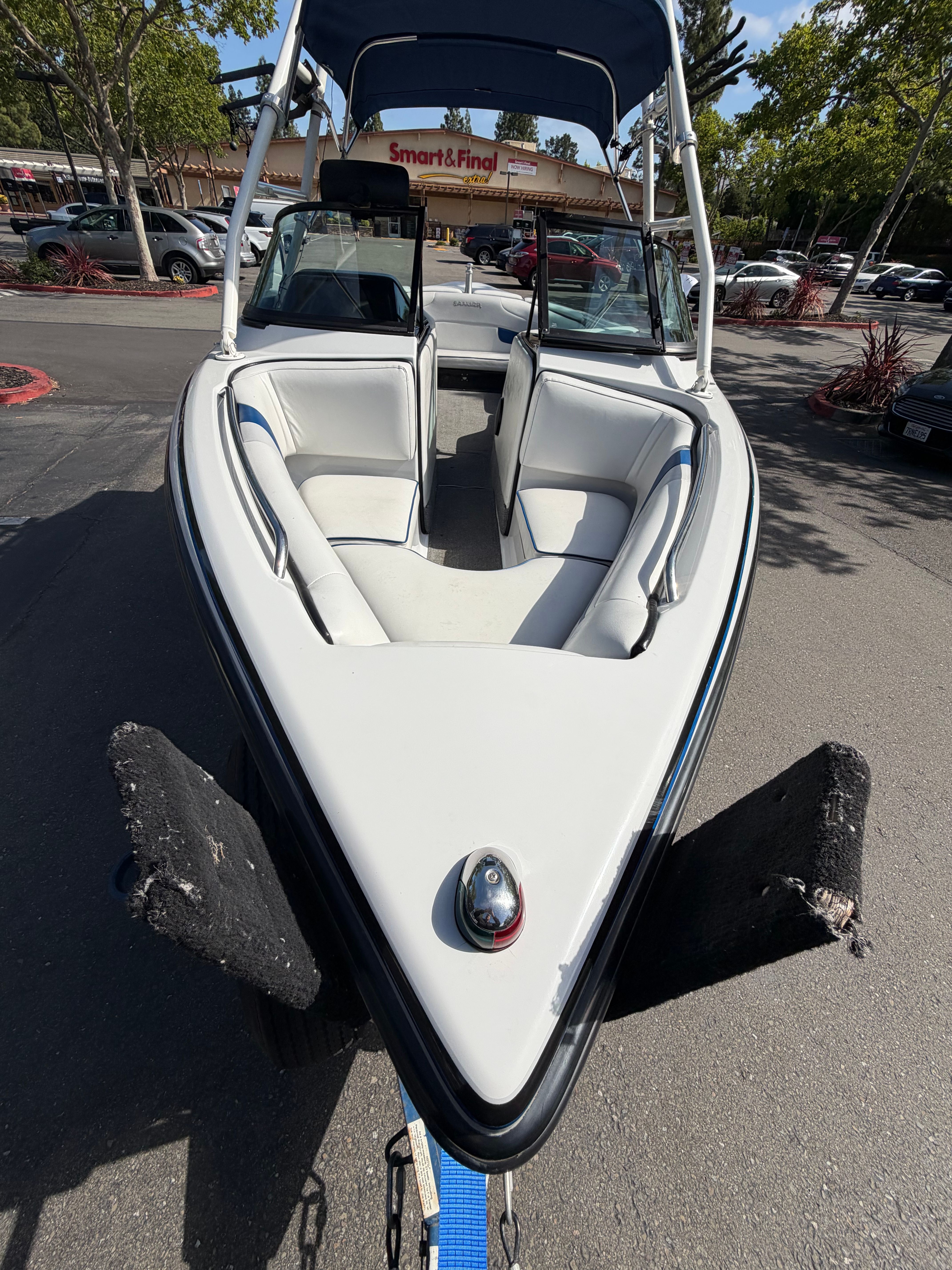 A 2001 Sanger V210 boat with white and blue interior, parked on a trailer.