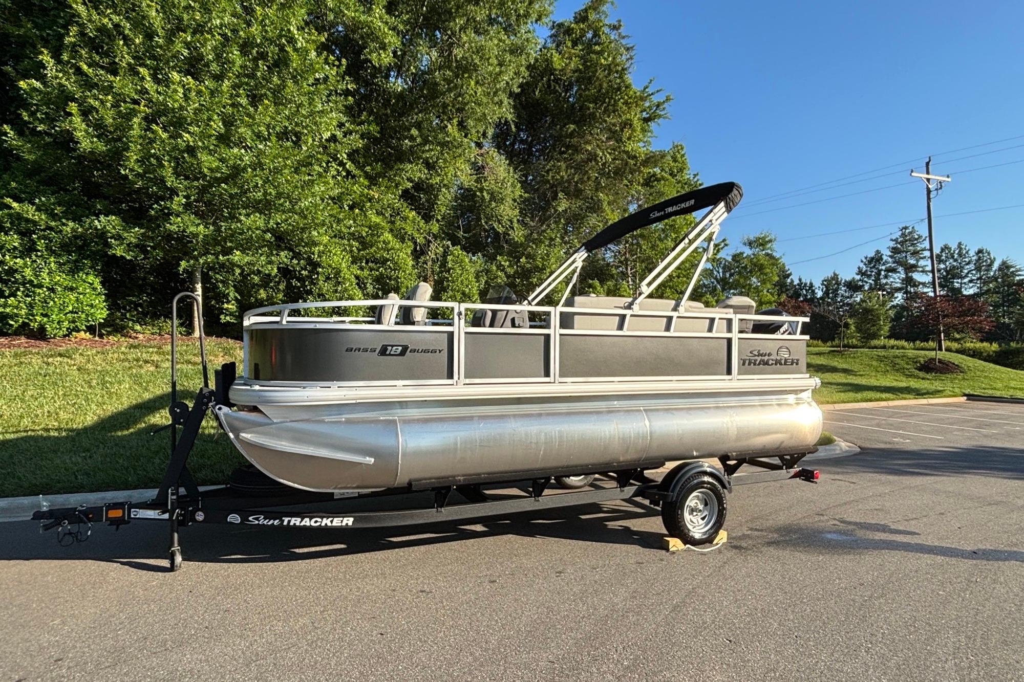 2026 Sun Tracker Bass Buggy 18 DLX pontoon boat on trailer, parked outdoors.