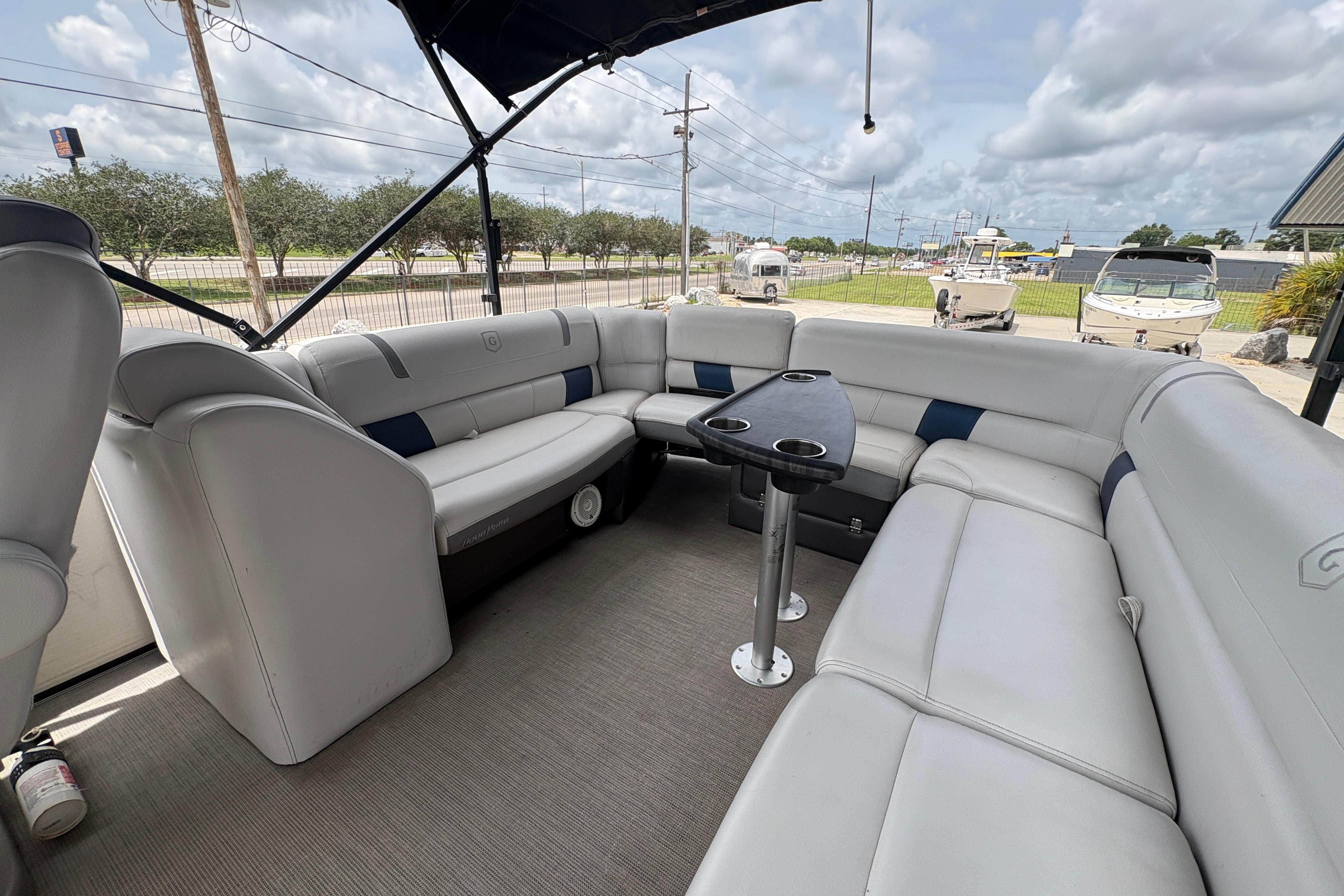 2019 Godfrey Aqua Patio boat interior with spacious seating and table, under a cloudy sky.