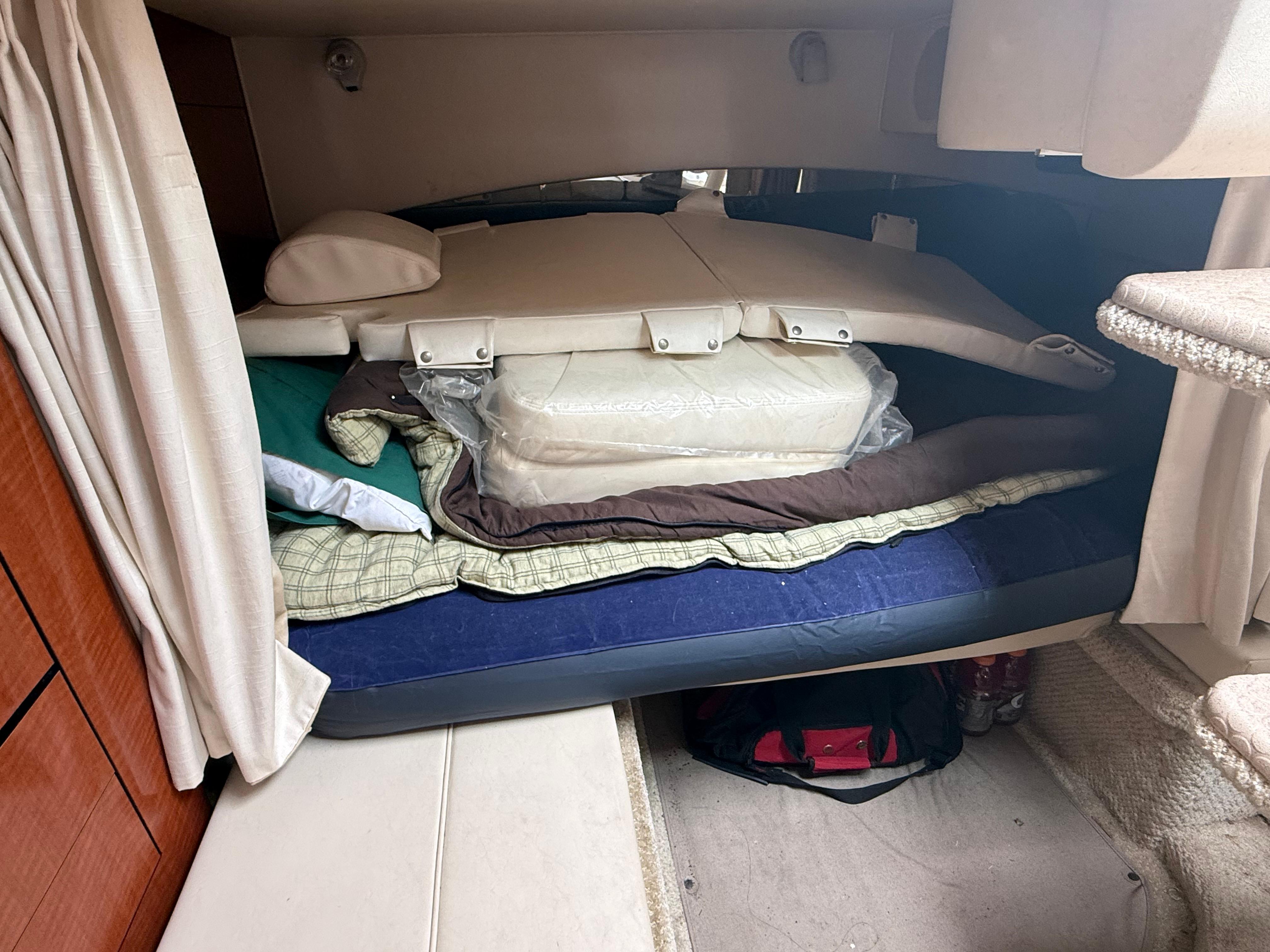2004 Sea Ray 300 Sundancer cabin with stacked bedding and cushions.