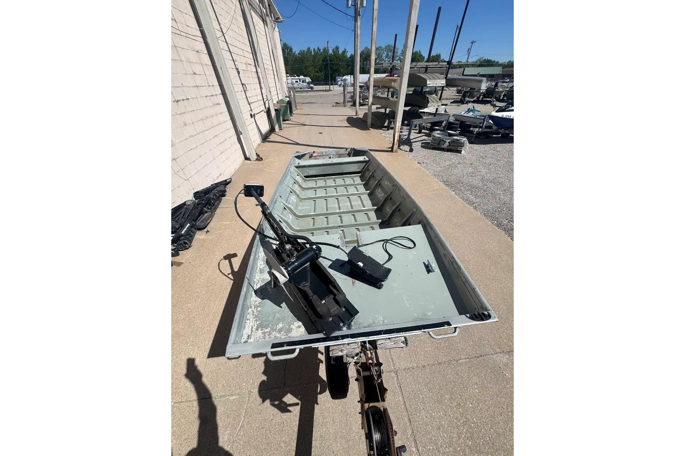 1973 Monark 14 Jon boat on trailer, parked outdoors under clear sky.
