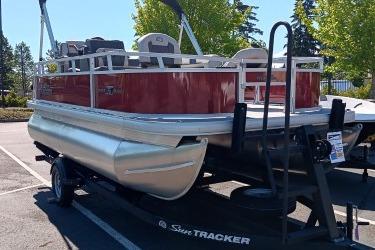 2026 Sun Tracker Bass Buggy 16 XL Select pontoon boat on trailer in parking lot.