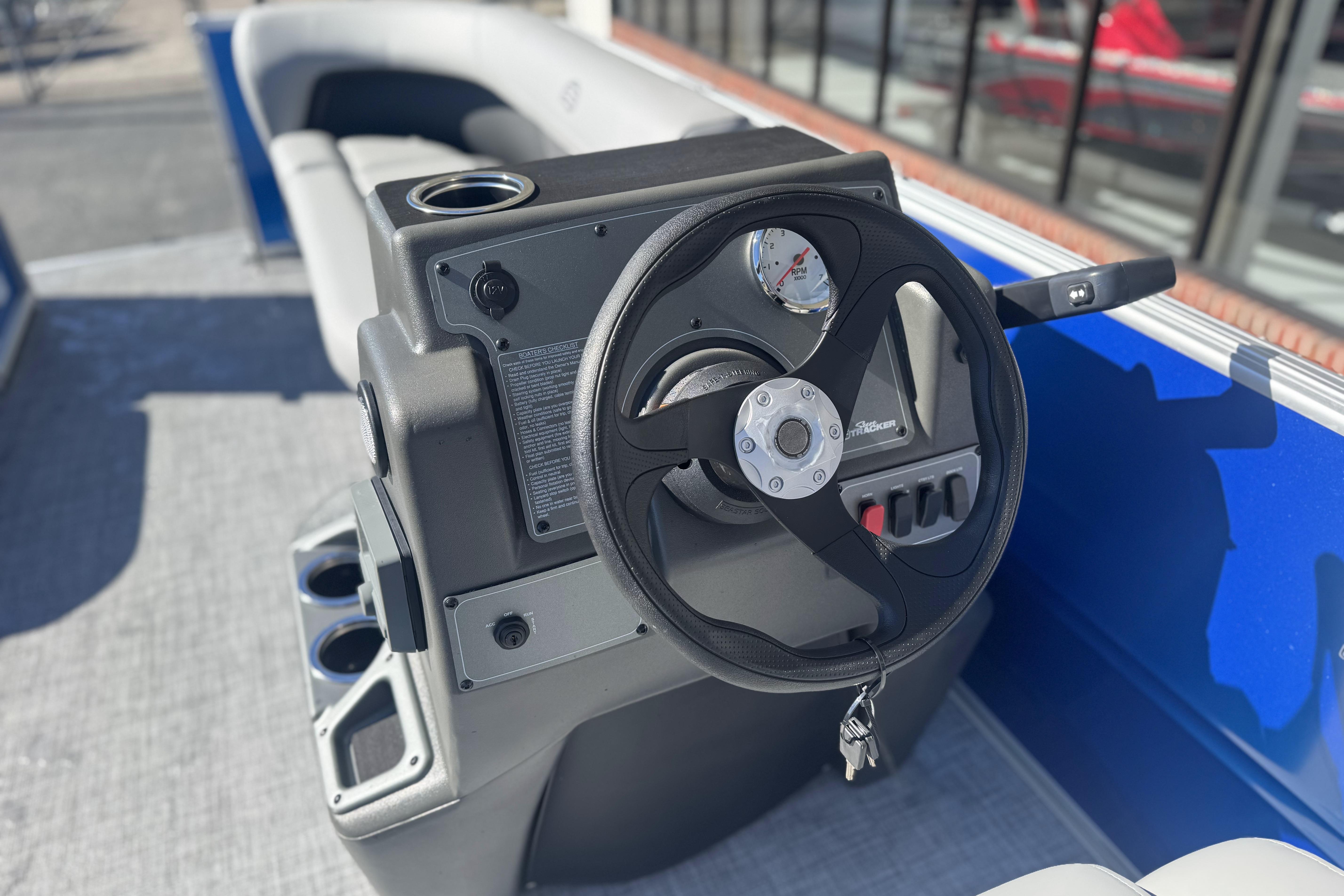2026 Sun Tracker Party Barge 16 DLX steering console with cup holders and gauges.