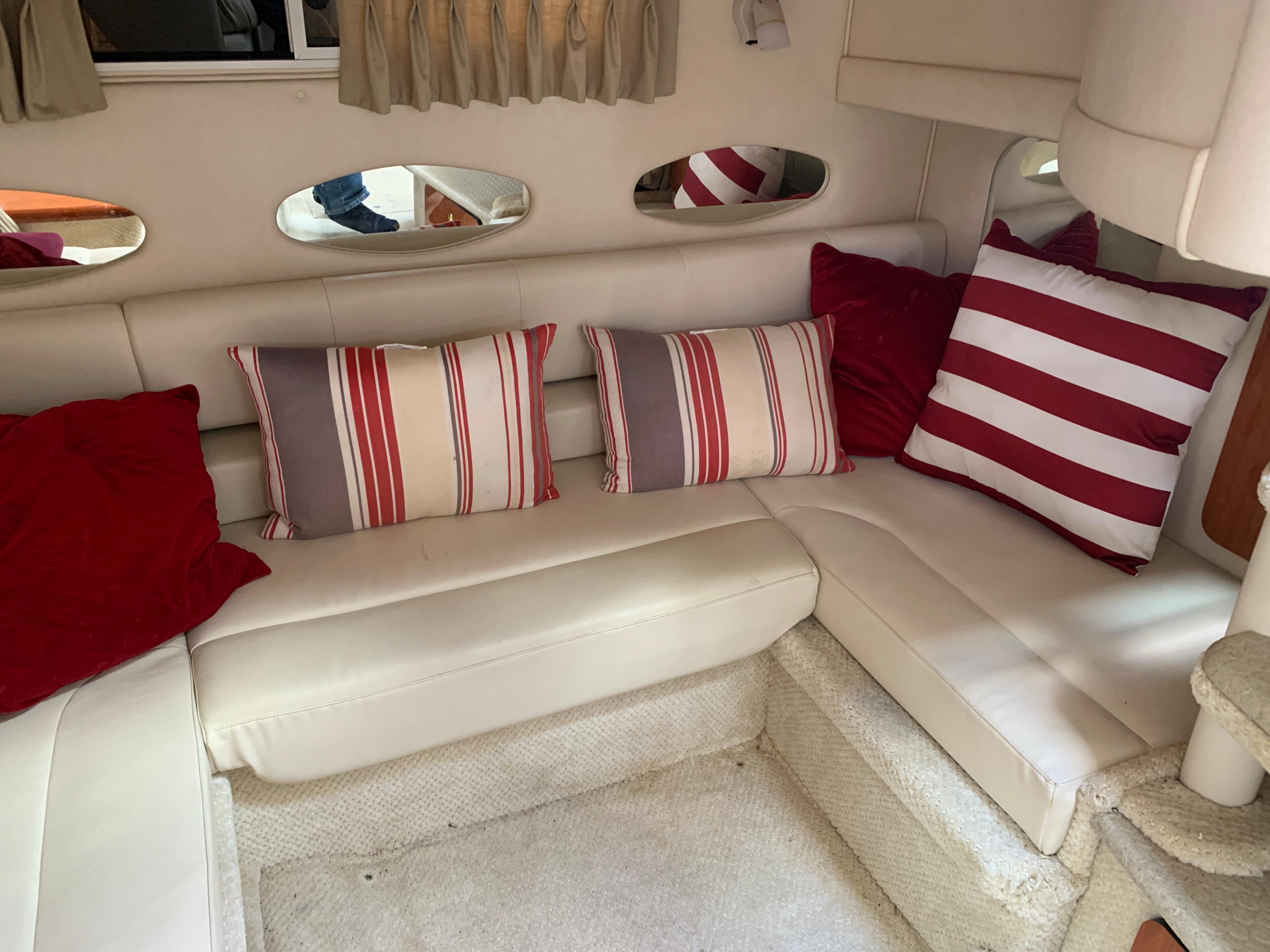 2001 Sea Ray 310 Sundancer interior with striped and solid red cushions on white seating.