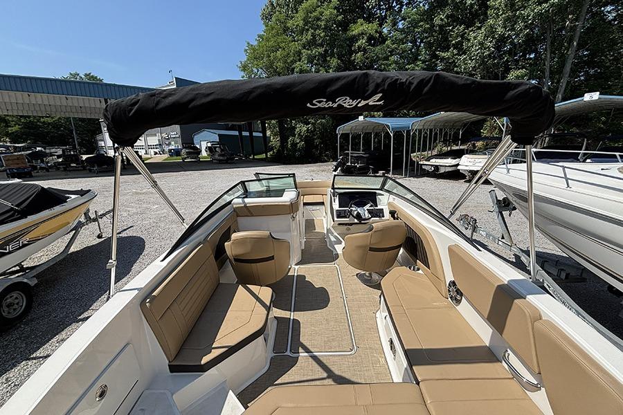 2019 Sea Ray SPX 230 Outboard boat with tan seating and black canopy in a marina.