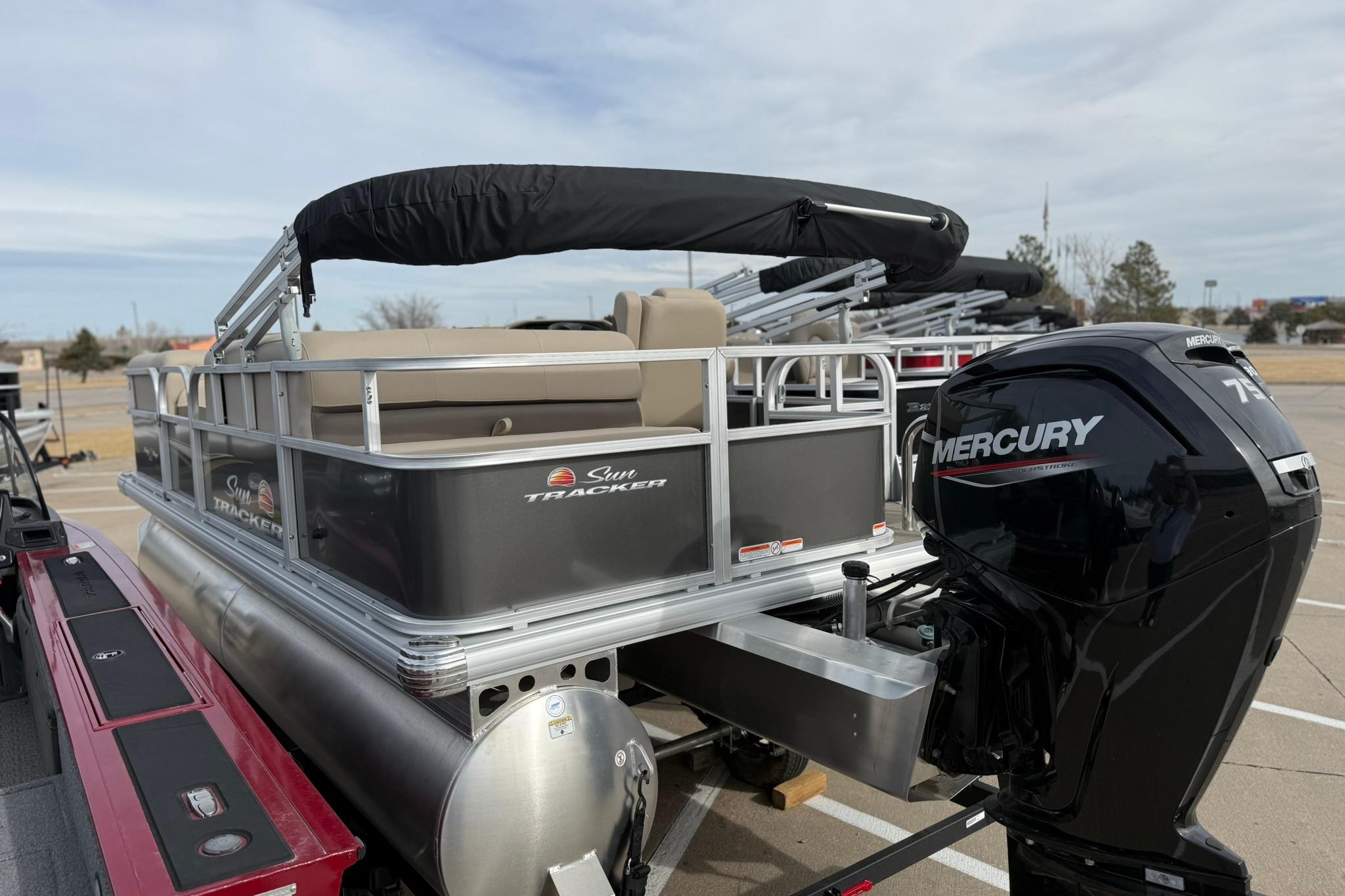 2025 Sun Tracker Party Barge 18 DLX pontoon boat with Mercury engine in parking lot.