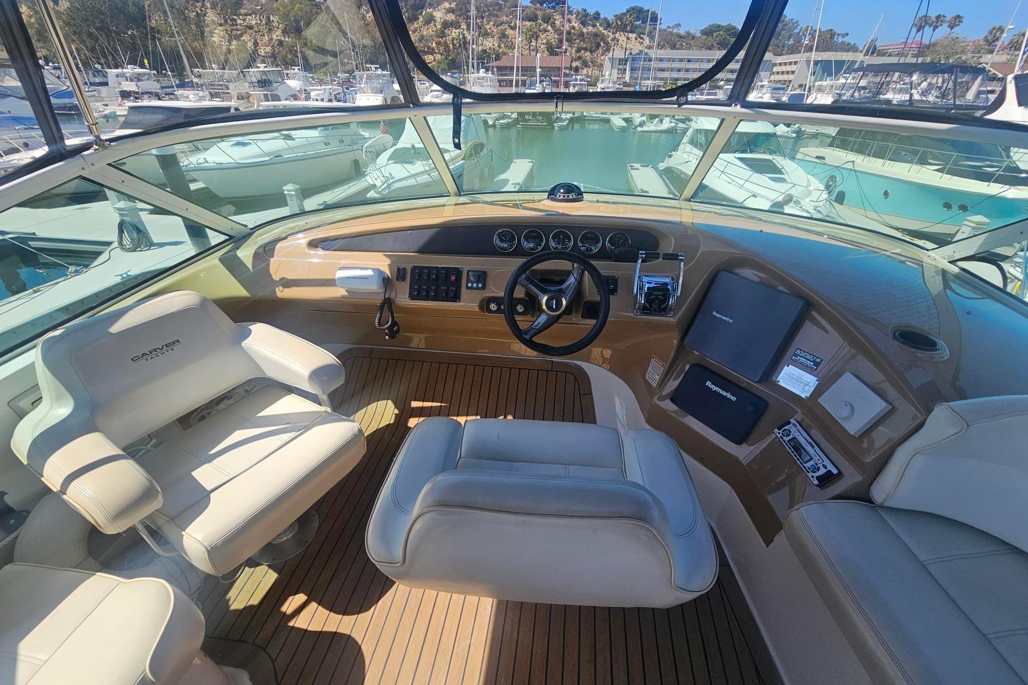 Pilothouse interior of 2002 Carver 450 Voyager, featuring helm and seating, docked at marina.