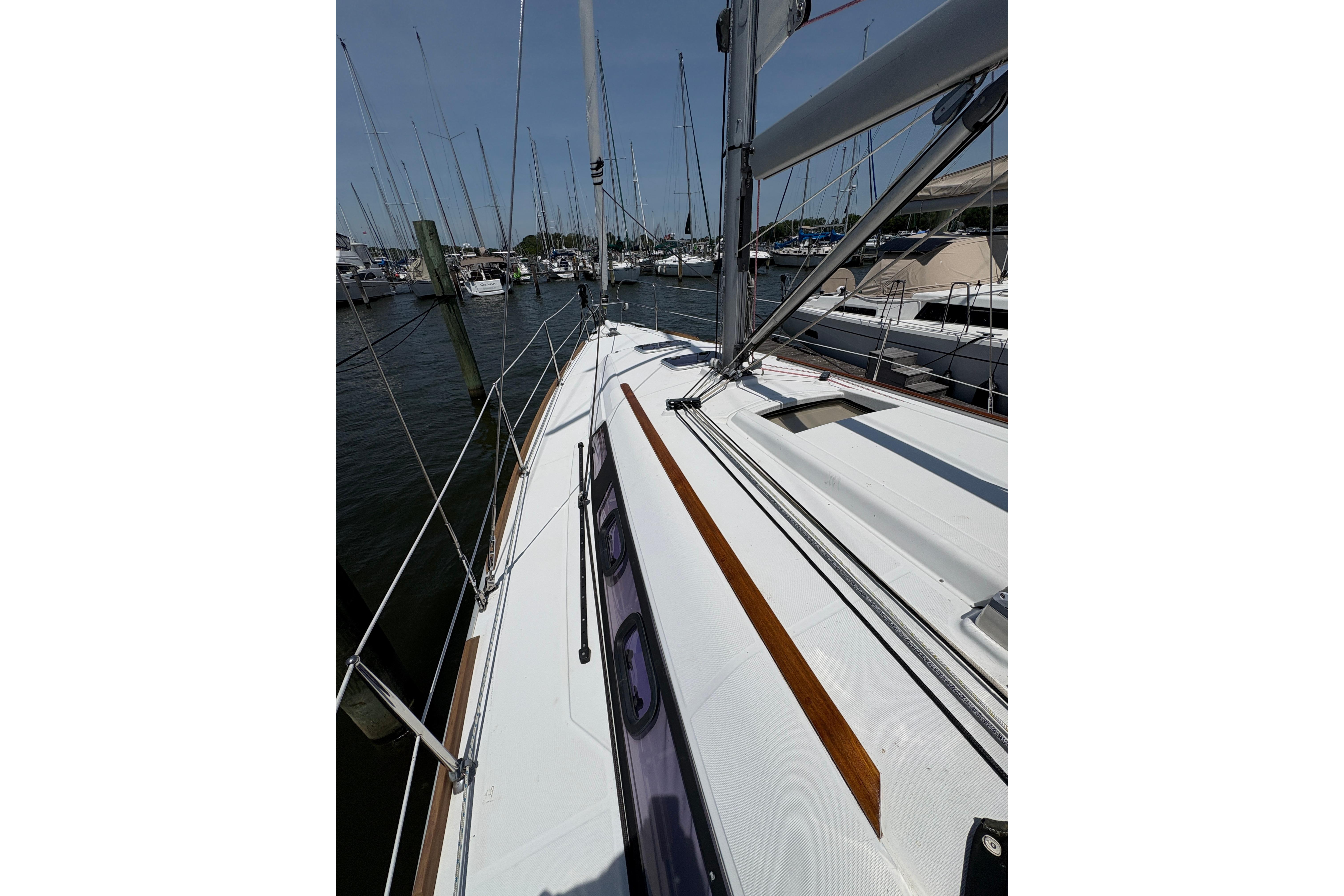 Beneteau Oceanis 34 sailboat deck, 2015 model, docked at marina under clear sky.